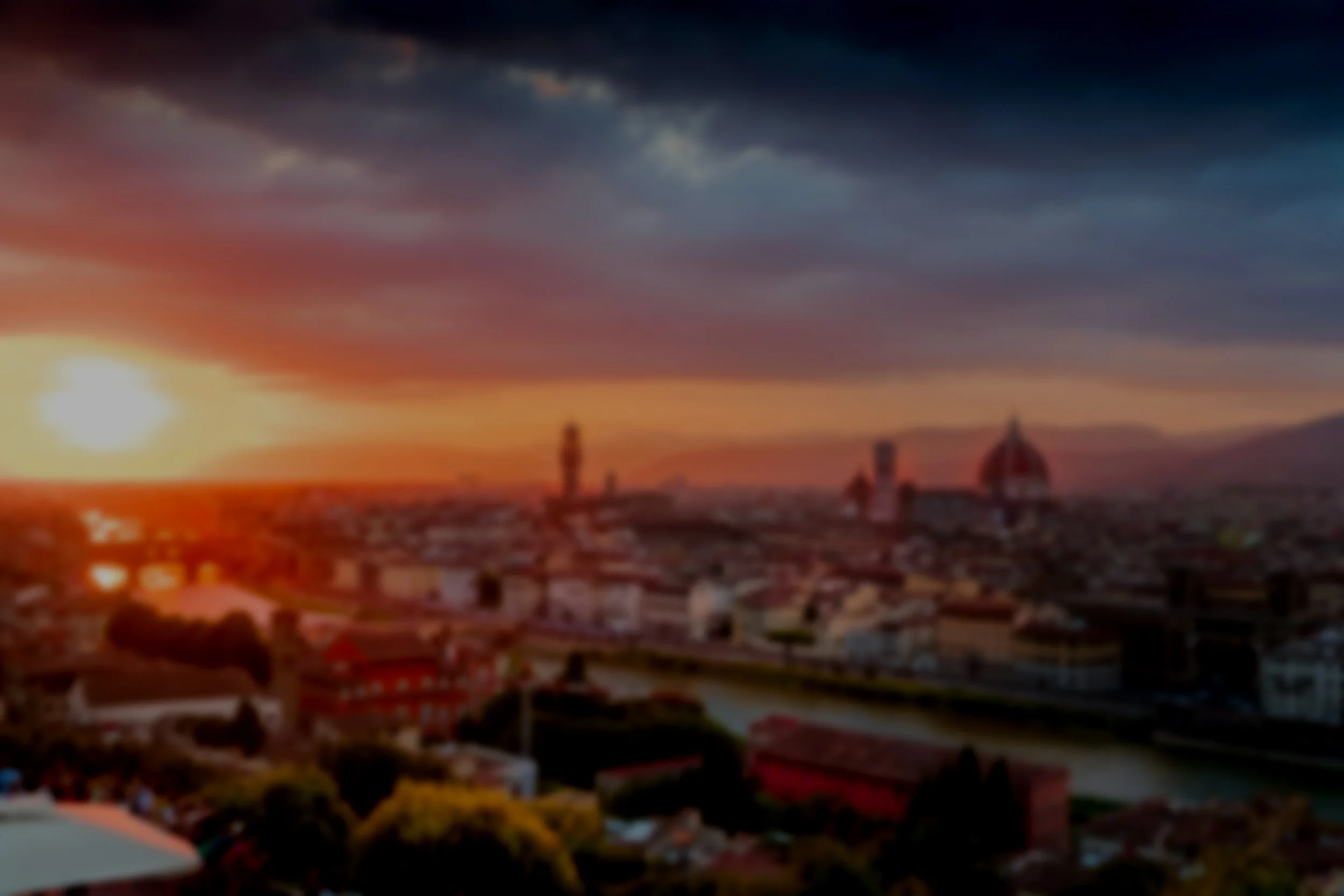 A city skyline at sunset with a colorful sky and prominent historic domed cathedral.