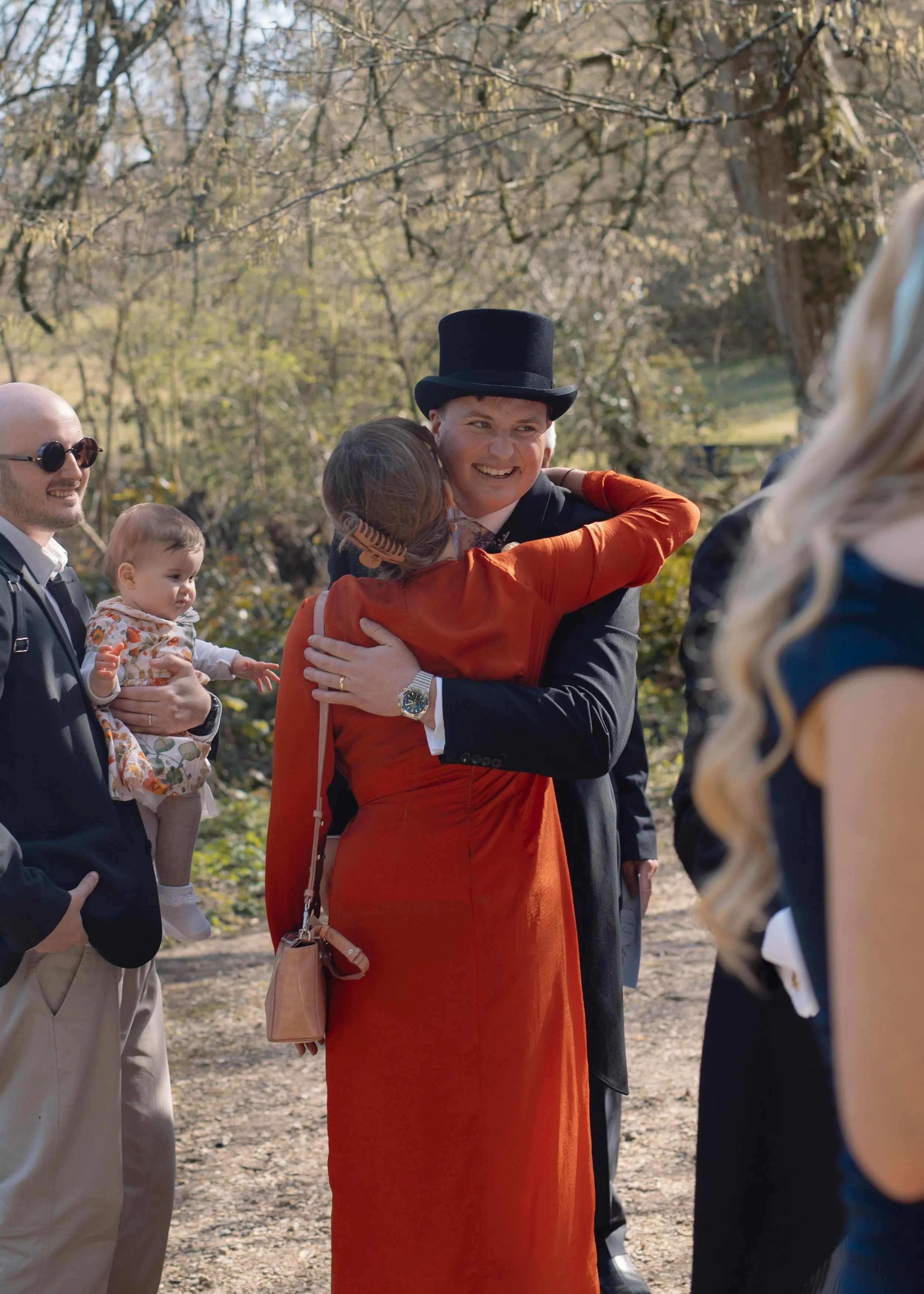 People sharing joyful embraces outdoors surrounded by trees and nature.