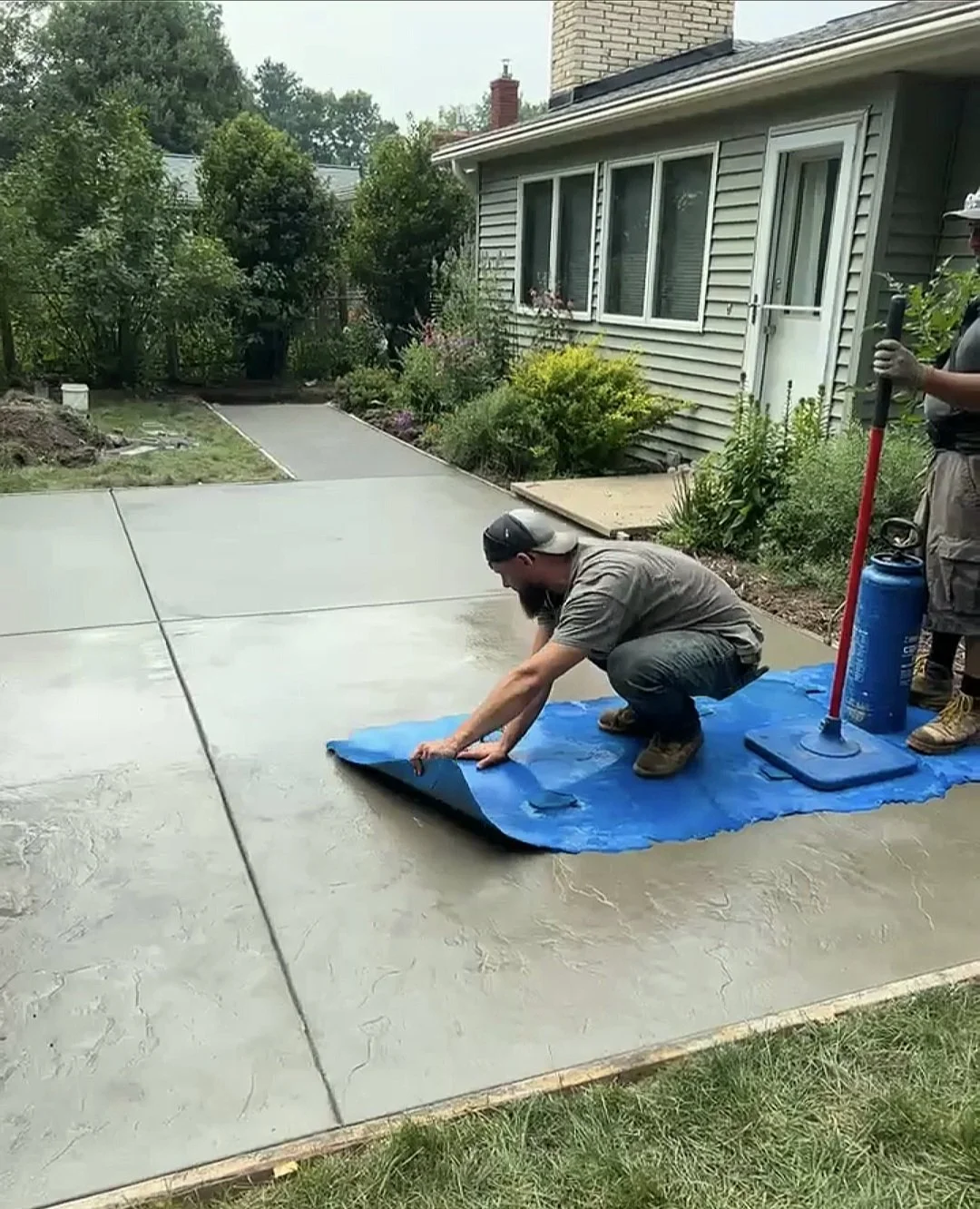 A modern house situated on a grassy hillside with snow-capped mountains in the background under a cloudy sky.