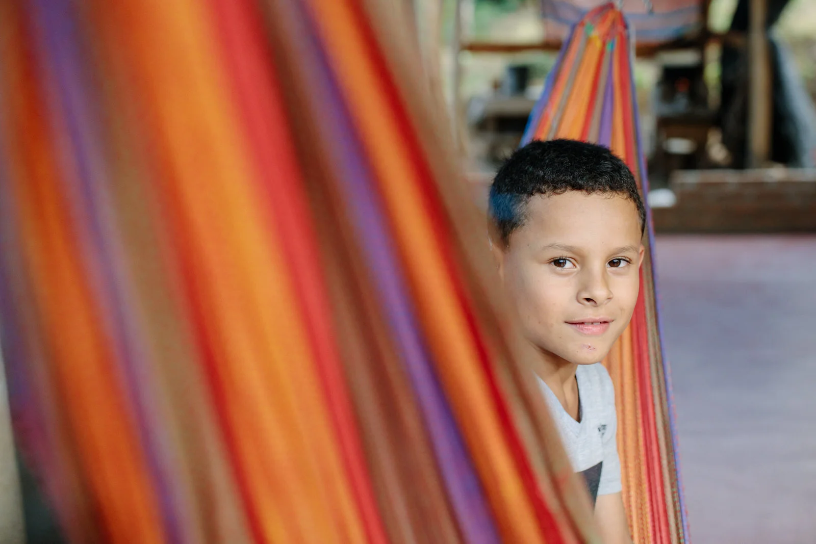 boy in colorful striped hammock posing for a portrait