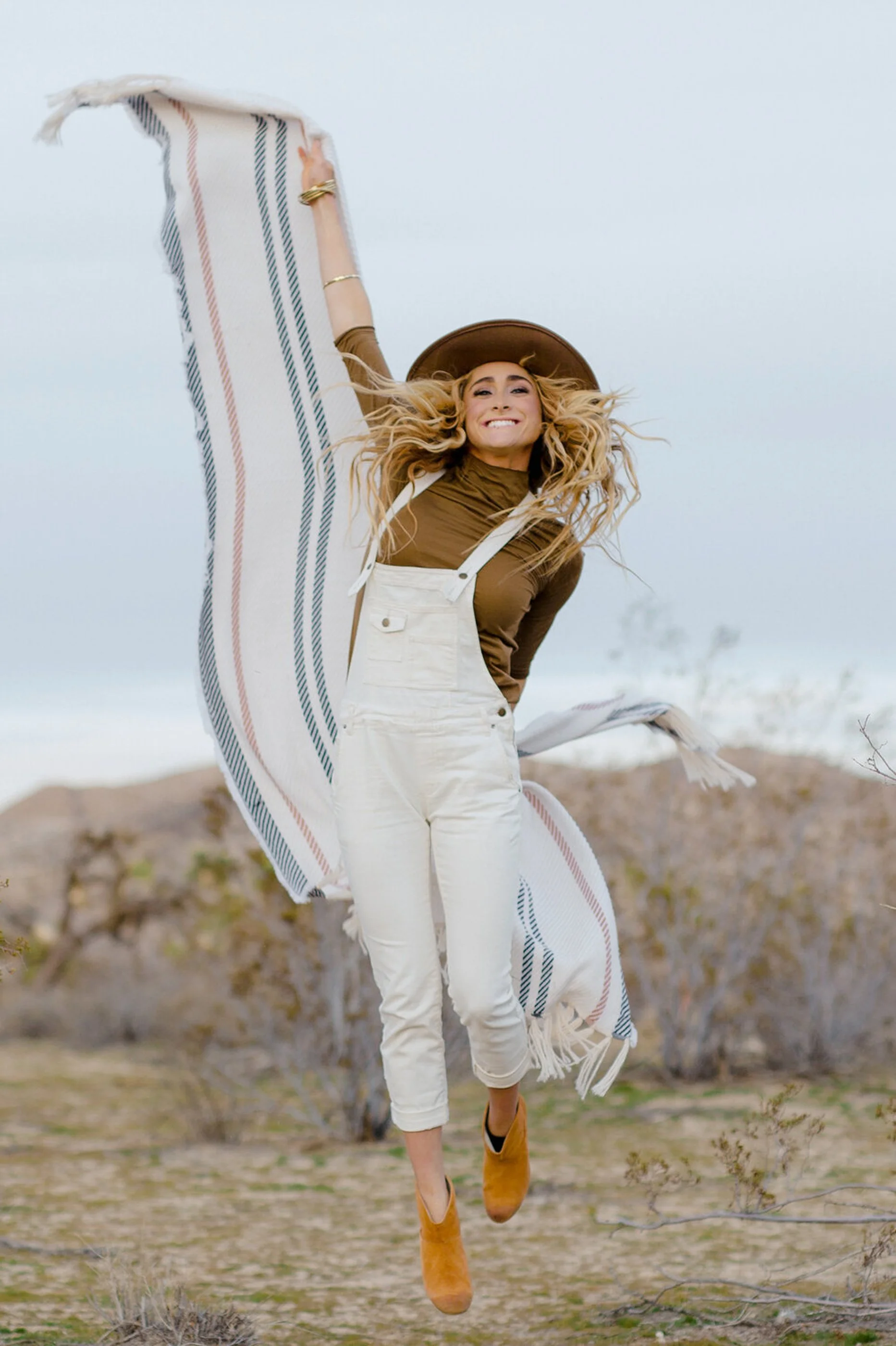 A lifestyle brand photo of a woman jumps in the dessert