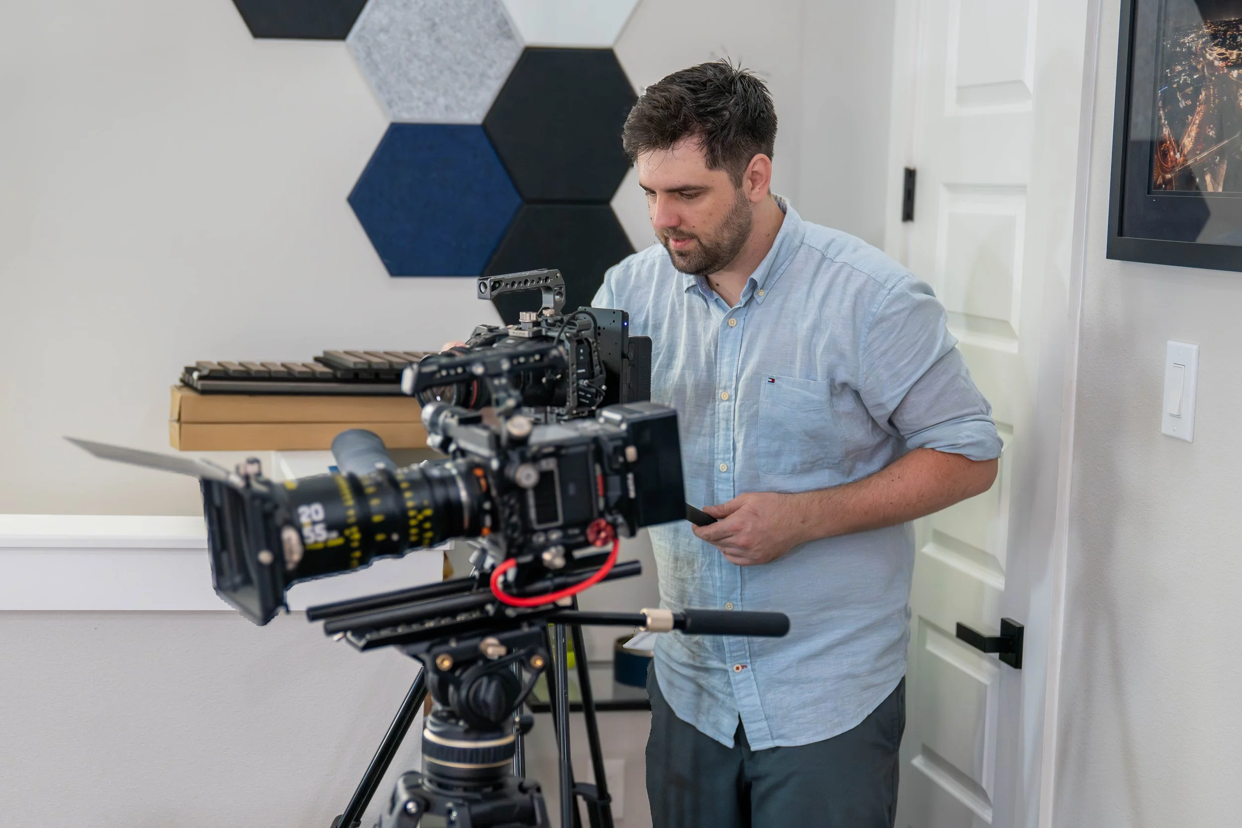 Videographer adjusting cinema camera setup in a modern studio with professional film equipment and acoustic wall panels in the background