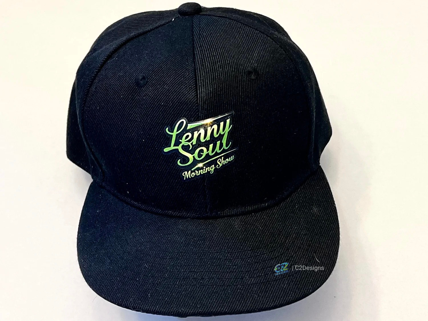 Black baseball cap with the words "Lenny Soul Morning Show" embroidered in green and white on the front