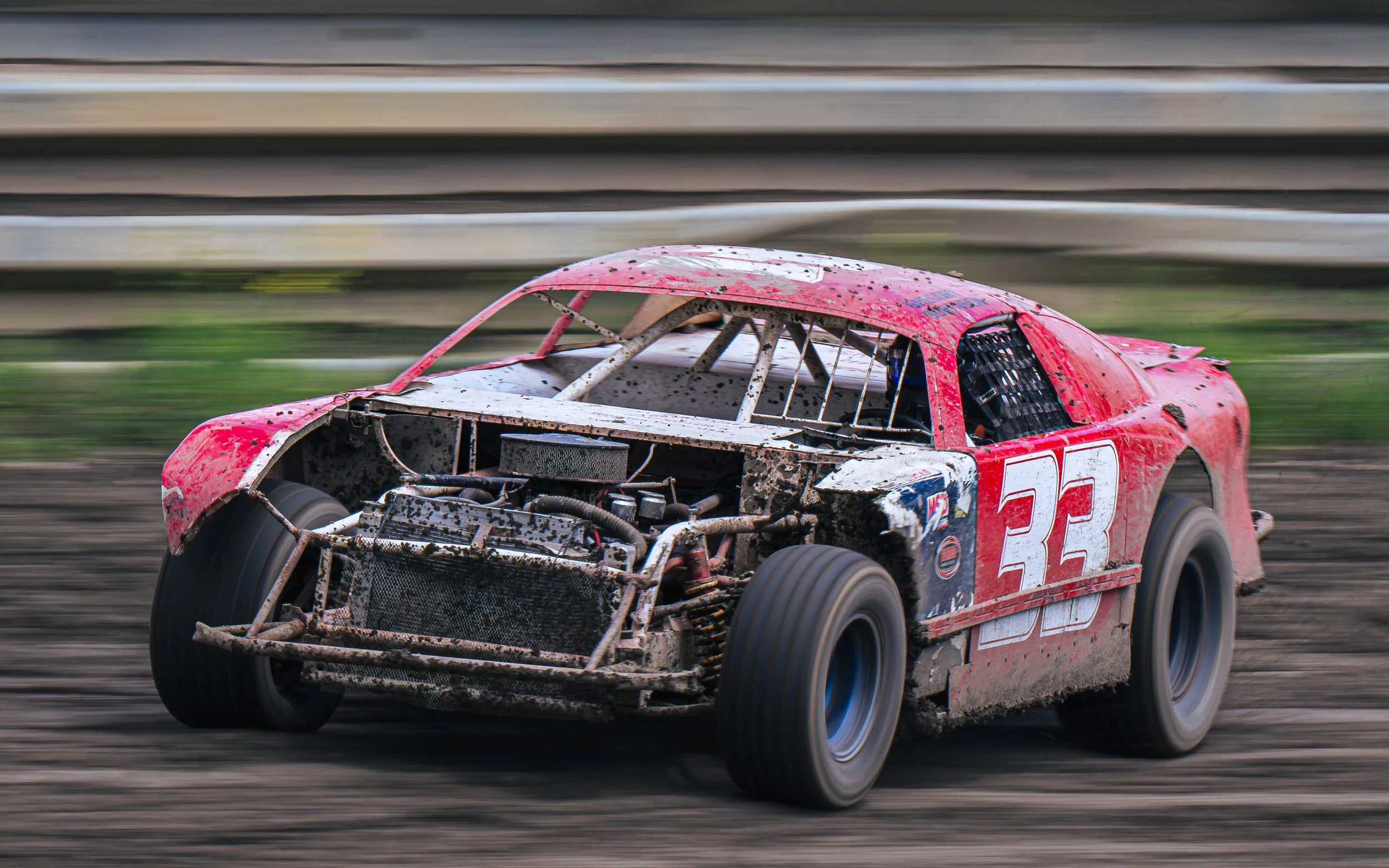 A dirt race car ( stock car ) with the number 33, covered in mud, speeding on a dirt track. Clearwater Speedway , Clearwater BC Canada