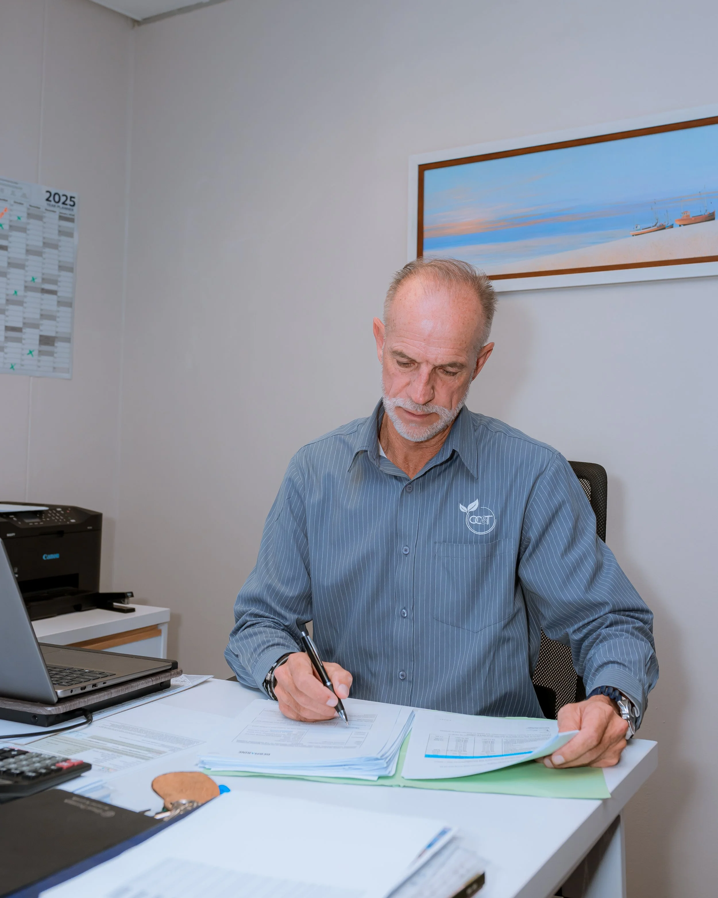 Three people sitting at a table with plates of salad, fruit, and glasses of water in a modern room. The person in the foreground is smiling and holding a fork with a salad. The other two are focused on their meals.