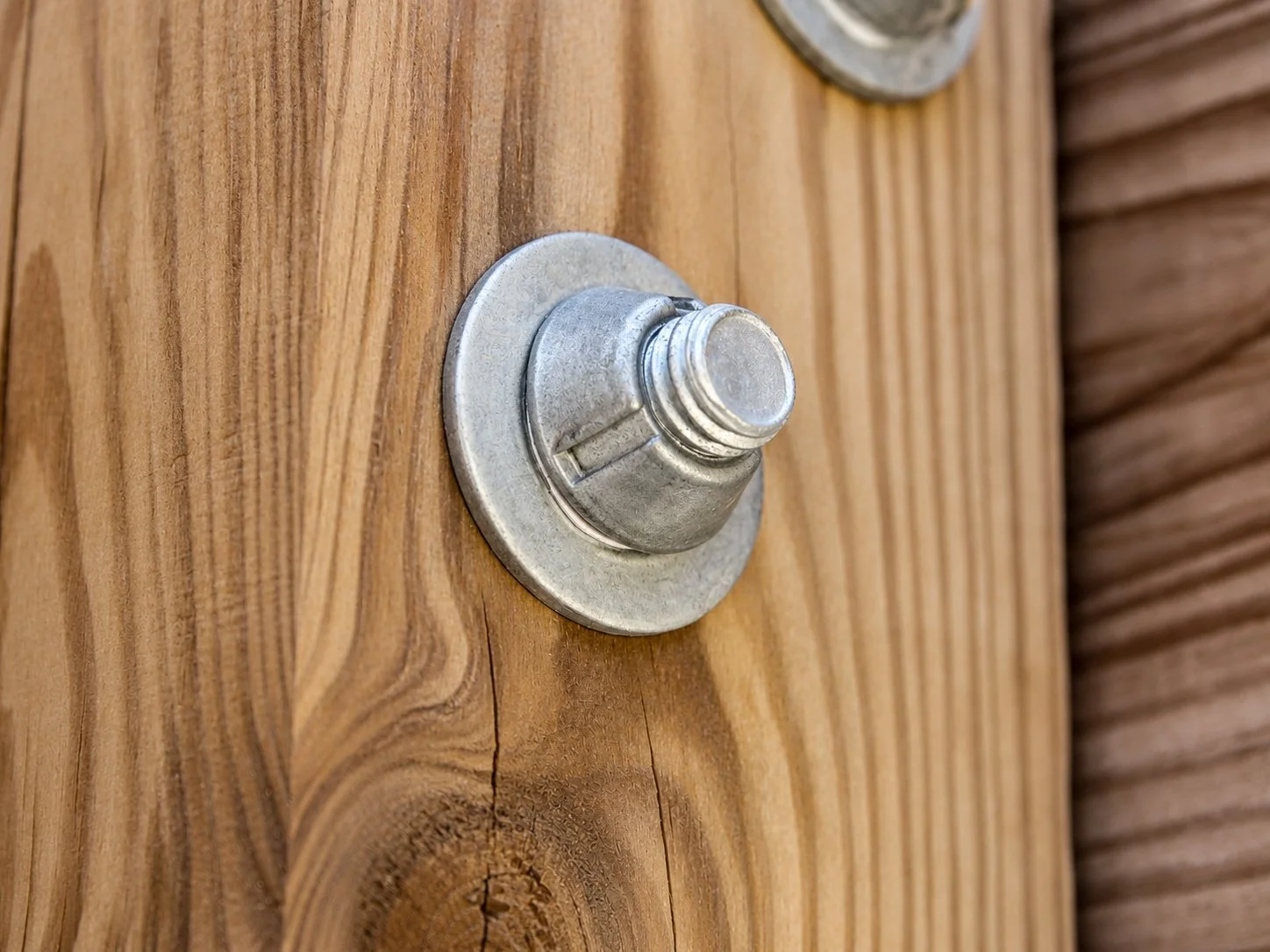 Tri-Groove tamper-resistant security nut installed on a threaded bolt against wood