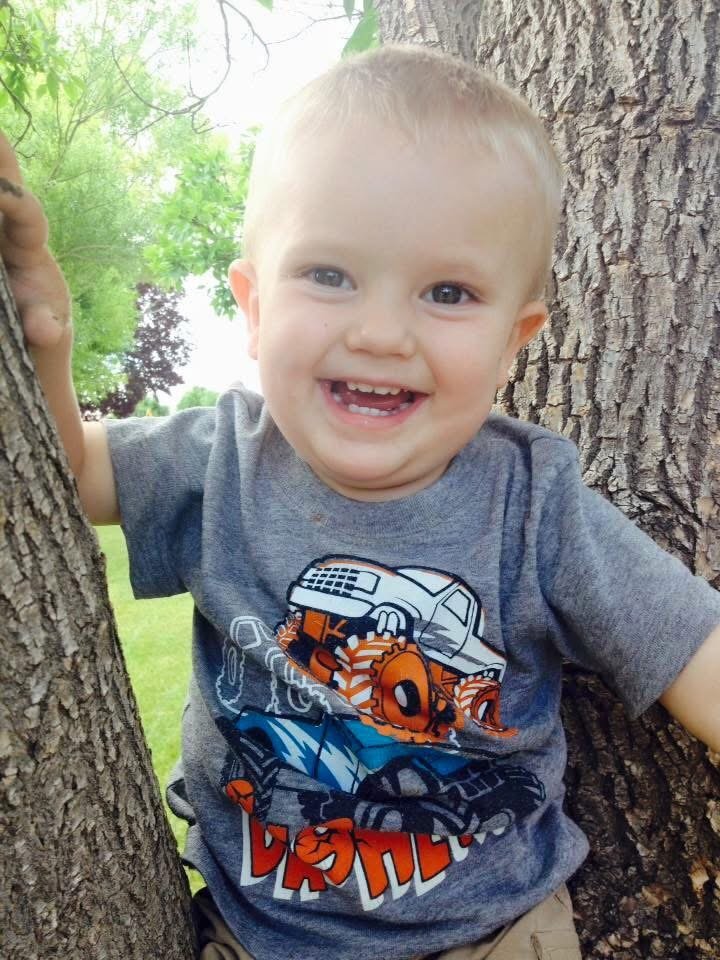 young child smiling while standing between two trees