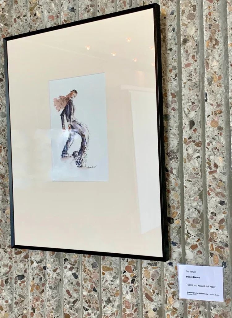 Ein gerahmtes Bild eines Streetdance-Tänzers, das in einer Ausstellung auf einer porösen Wand hängt.