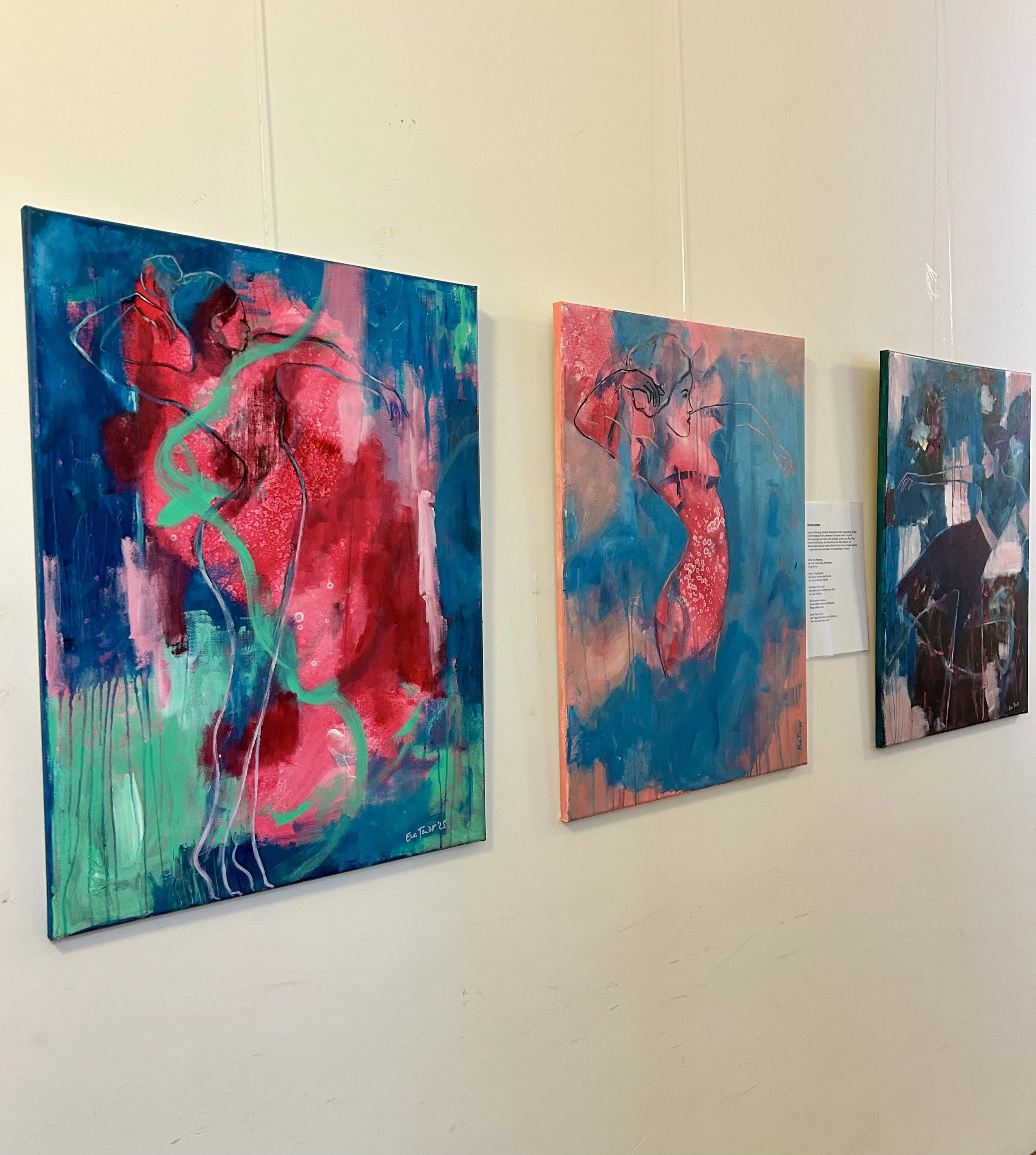 Drei bunte abstrakte Gemälde von Frauen in einer Galerie aufgehängt.