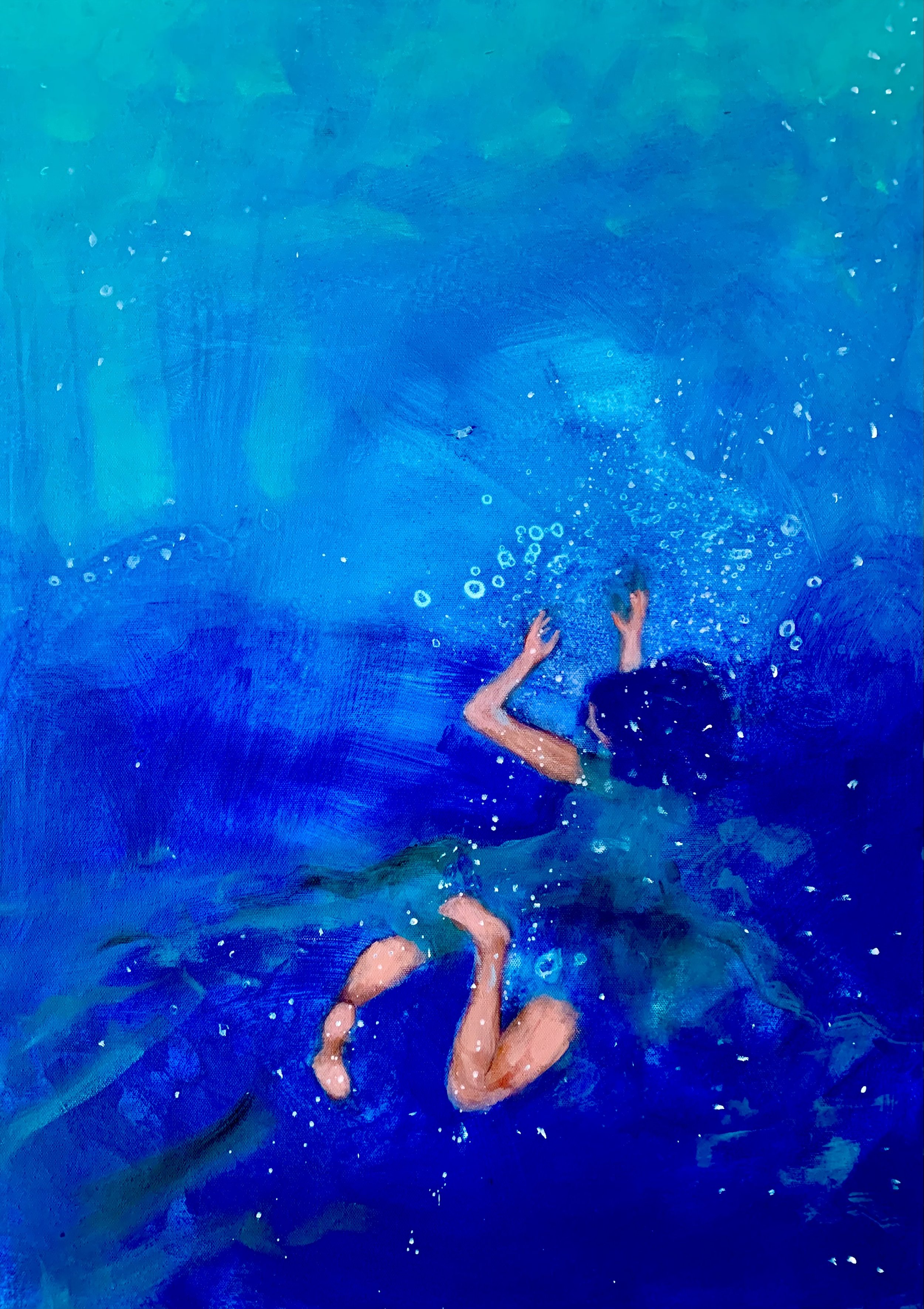 Ein Junge schwimmt im blauen Wasser und taucht mit Wasserblasen umgeben