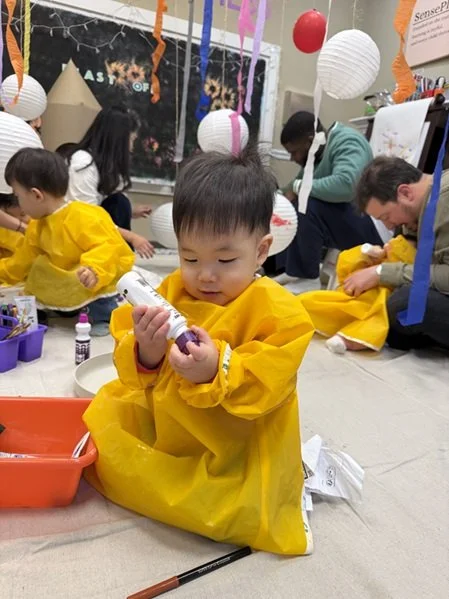 A kid weating a smock playing with paint stamp