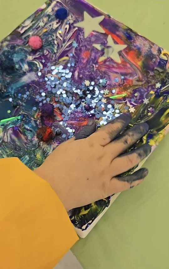 a hand playing with glitter and paint
