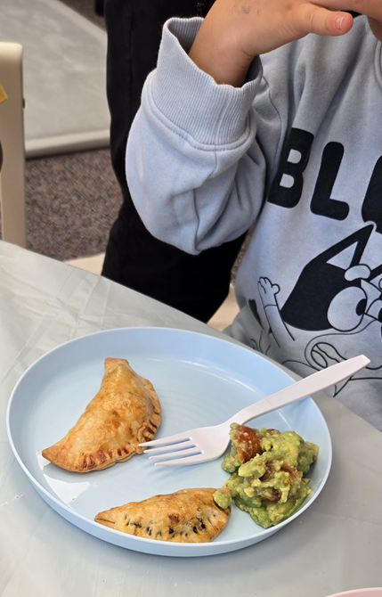 a kid eating empanada and guacamole