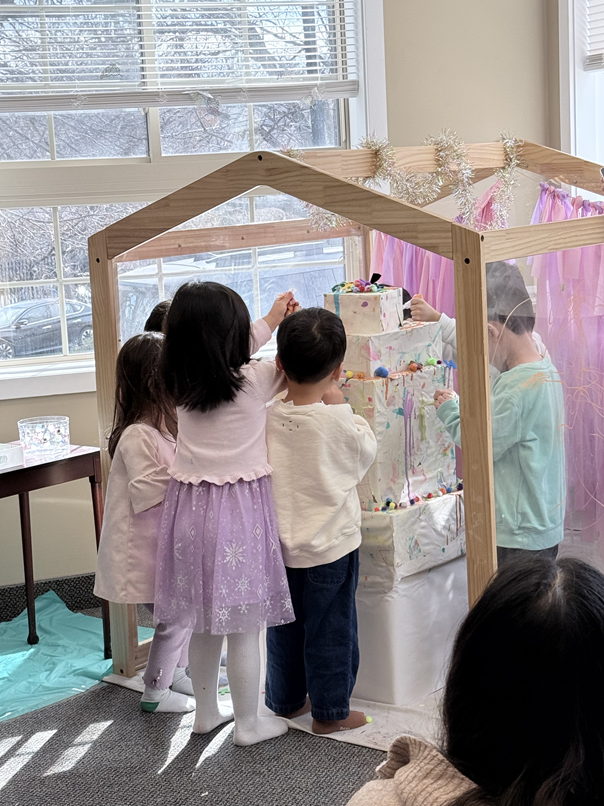 Kids decorating birthday cake in acrylic pane house
