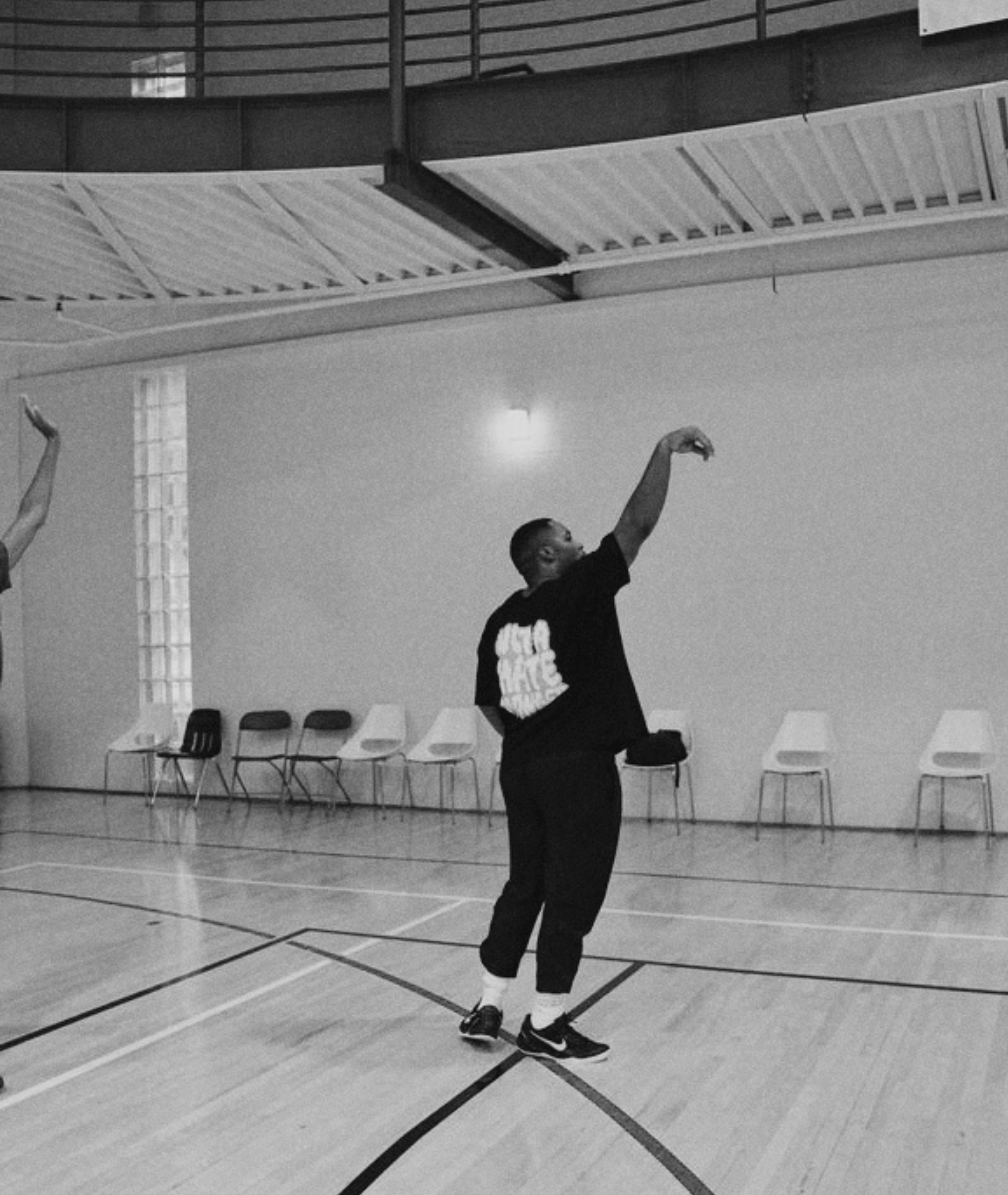 Black and white photo of a basketball player shooting in an indoor gymnasium
