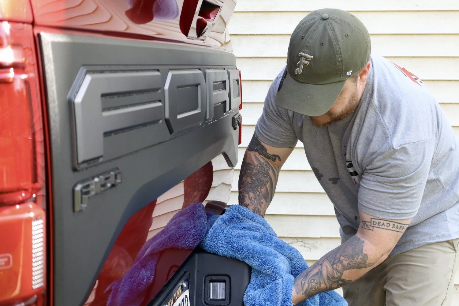 A detailing is drying a truck that has just had and exterior and interior cleaning completed. The red paint show gloss and reflections from the ceramic coating.