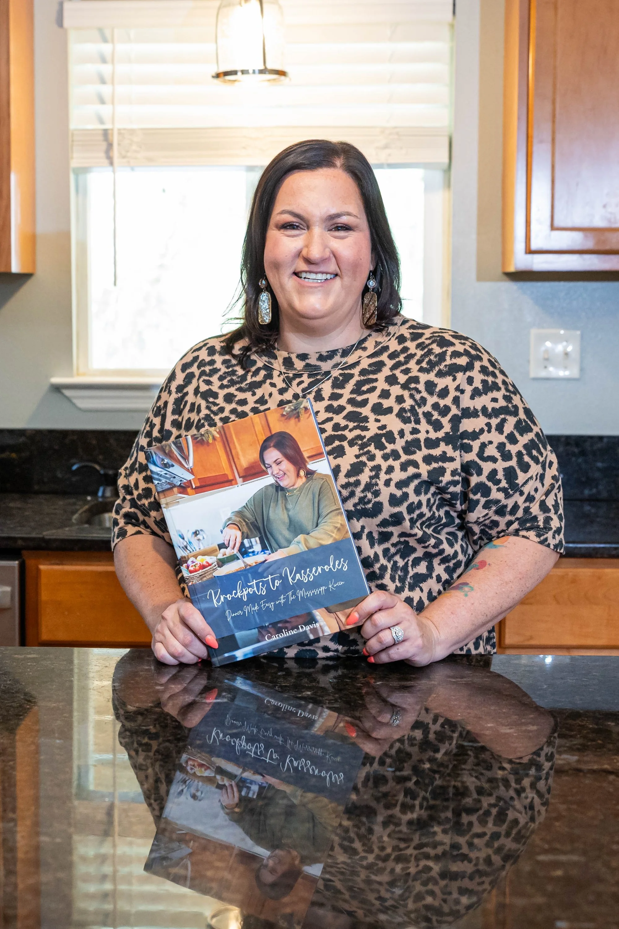 smiling-woman-in-a-leopard-print-blouse-holding-a-cookbook-i.jpg