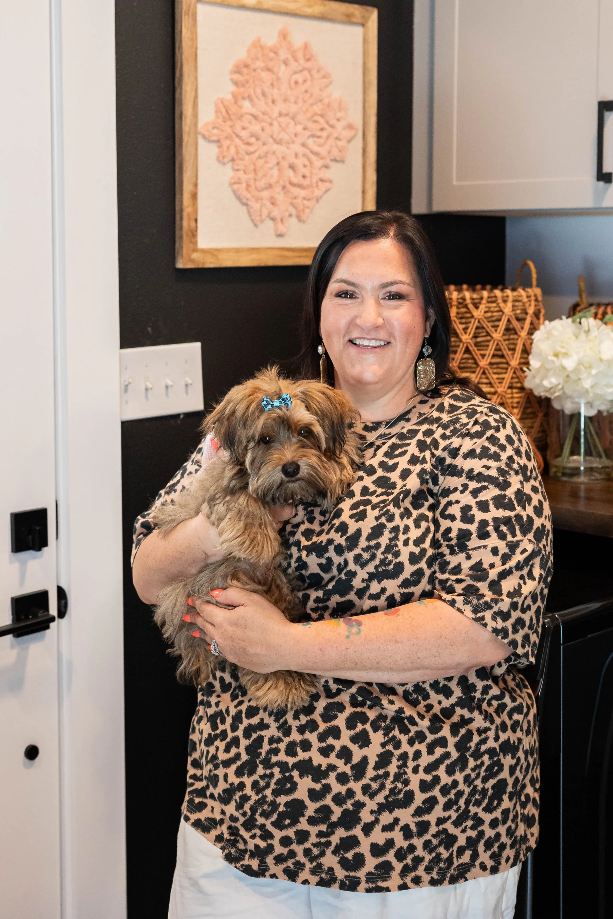 woman-in-leopard-print-holding-furry-dog-with-blue-bow-smili.jpg