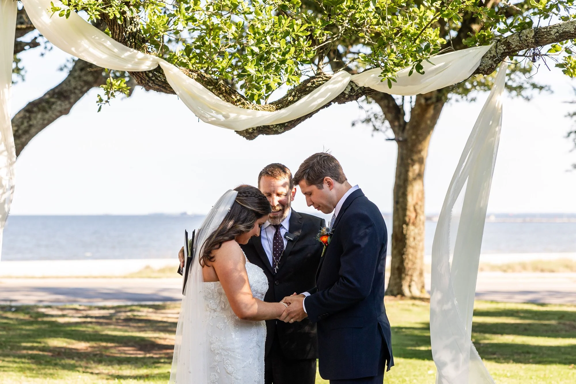 bride-and-groom-hold-hands-during-an-outdoor-ceremony-beneat.jpg