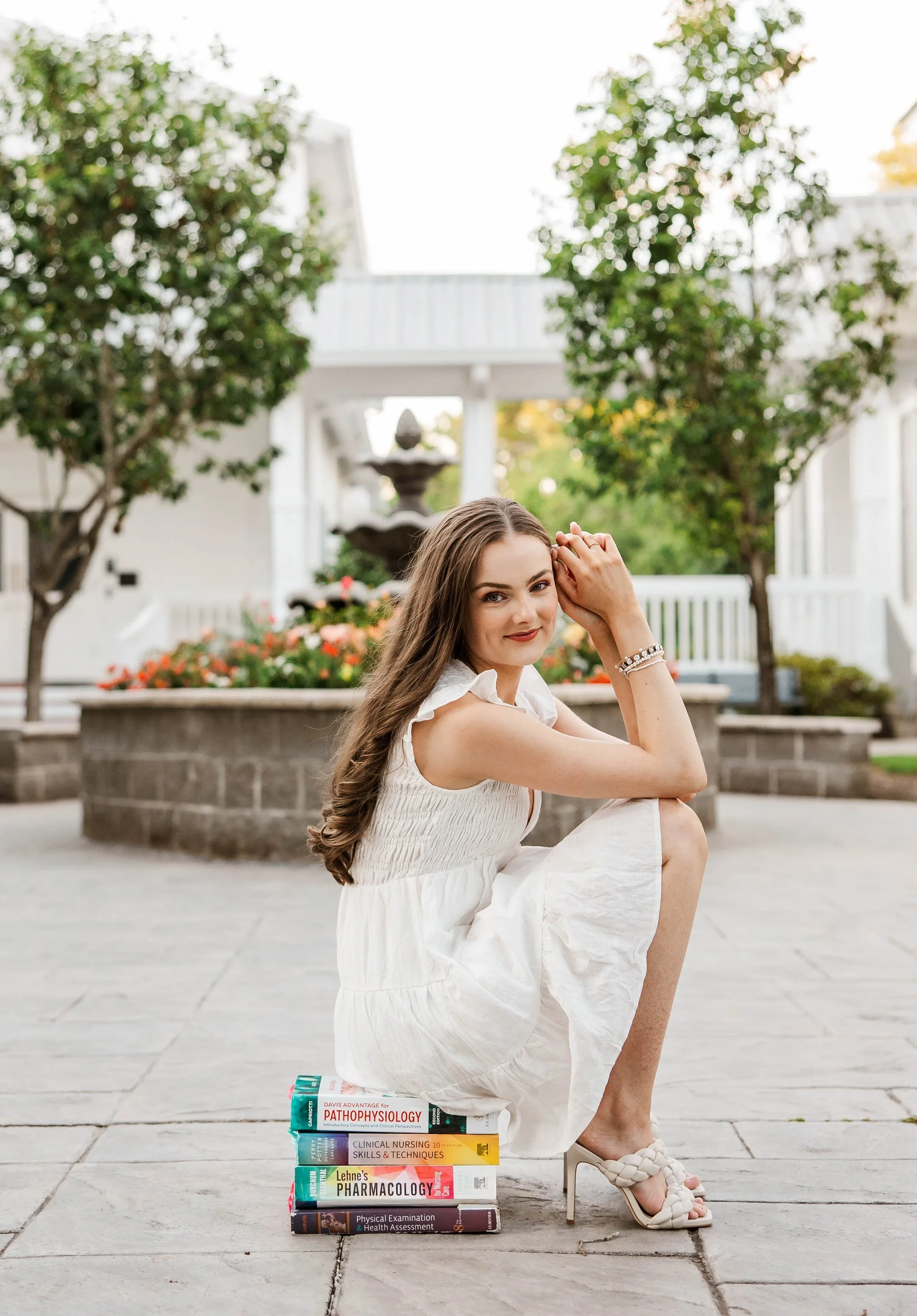 woman-in-white-dress-crouching-on-textbooks-smiling-in-a-gar.jpg