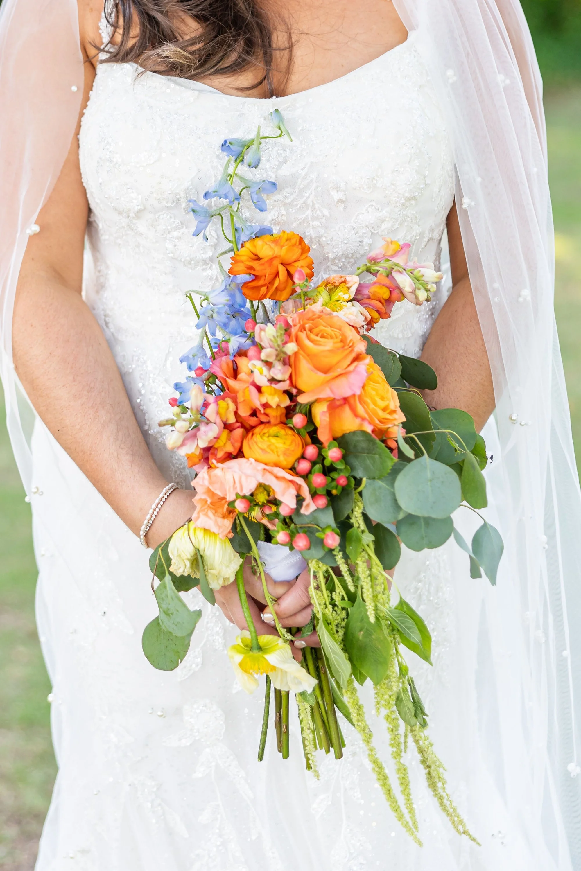 bride-holding-a-vibrant-bouquet-with-orange-pink-and-blue-fl.jpg