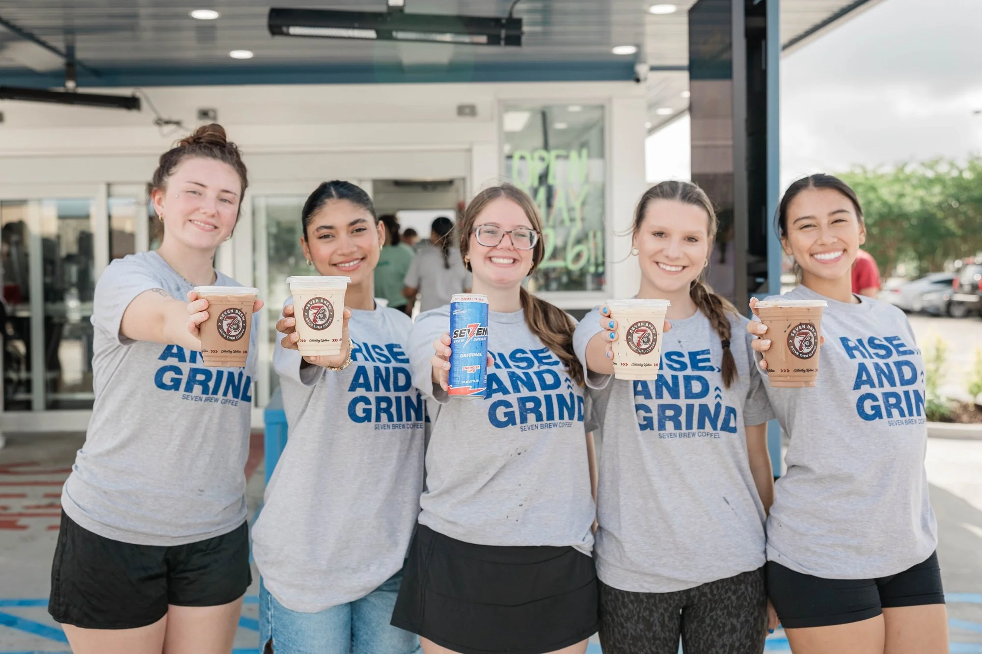 five-people-smiling-holding-drinks-wearing-matching-rise-and.jpg