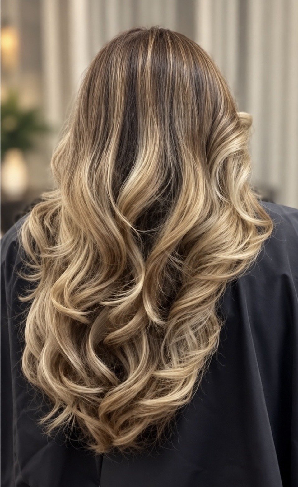 Dimensional blonde balayage with soft, voluminous waves and natural brunette roots, styled by Grace at Inwood Hair Studio in Manhattan, NYC.