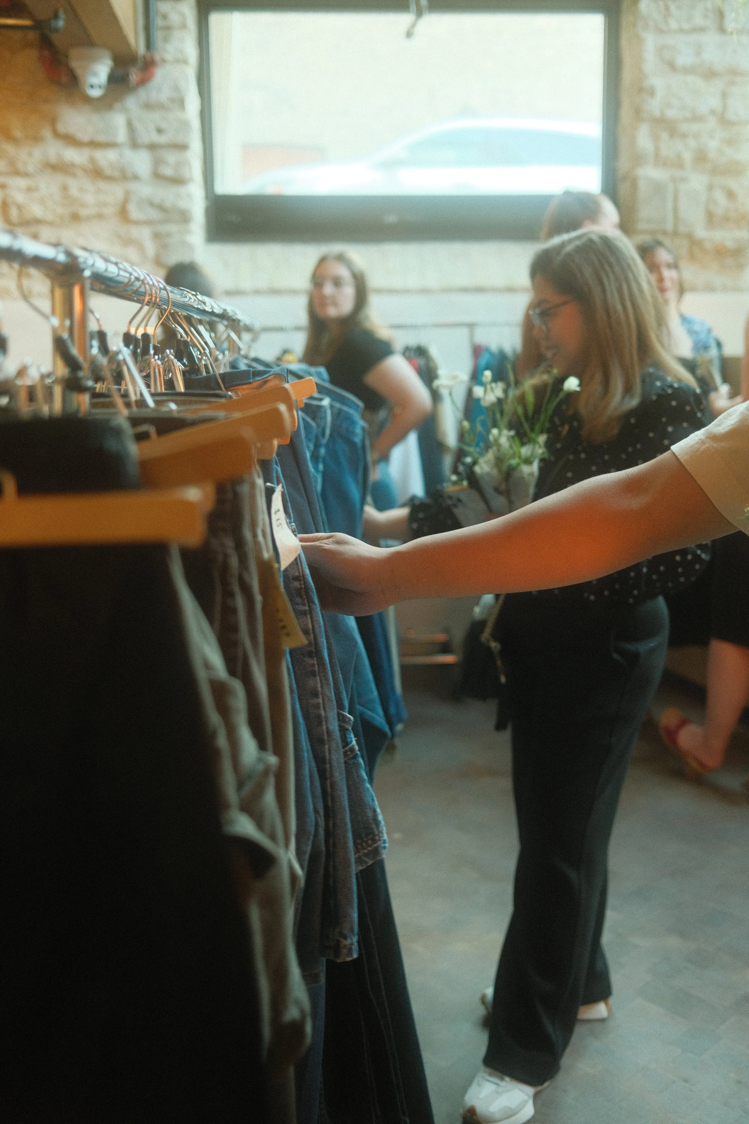 People shopping in a clothing store, browsing through racks of jeans and pants.