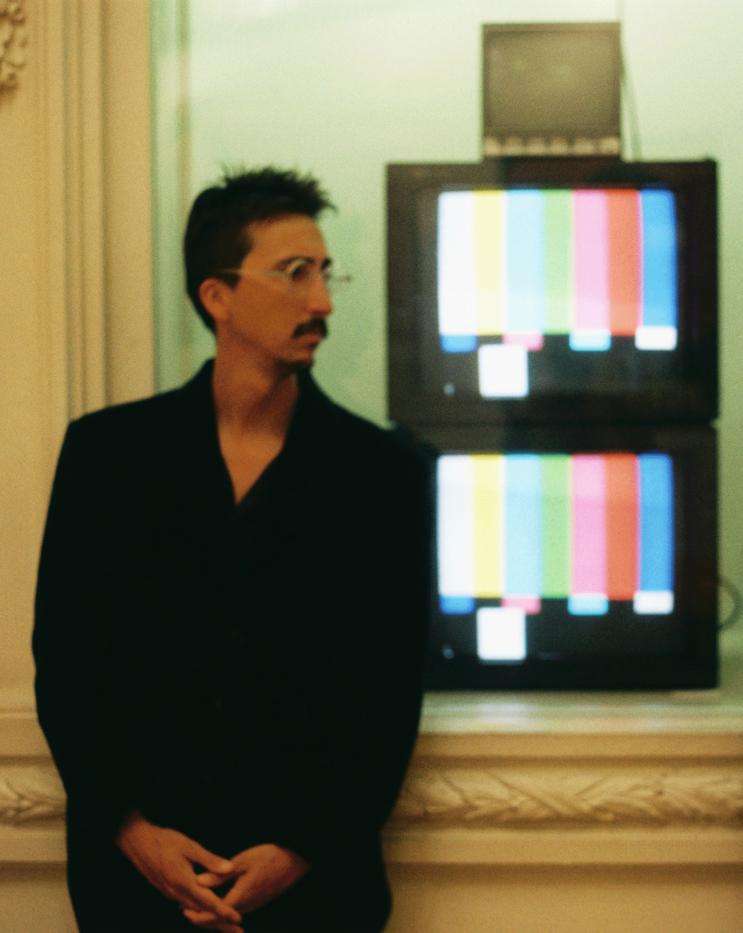 Dr. Saiz standing next to 2 tv screens with color bars.