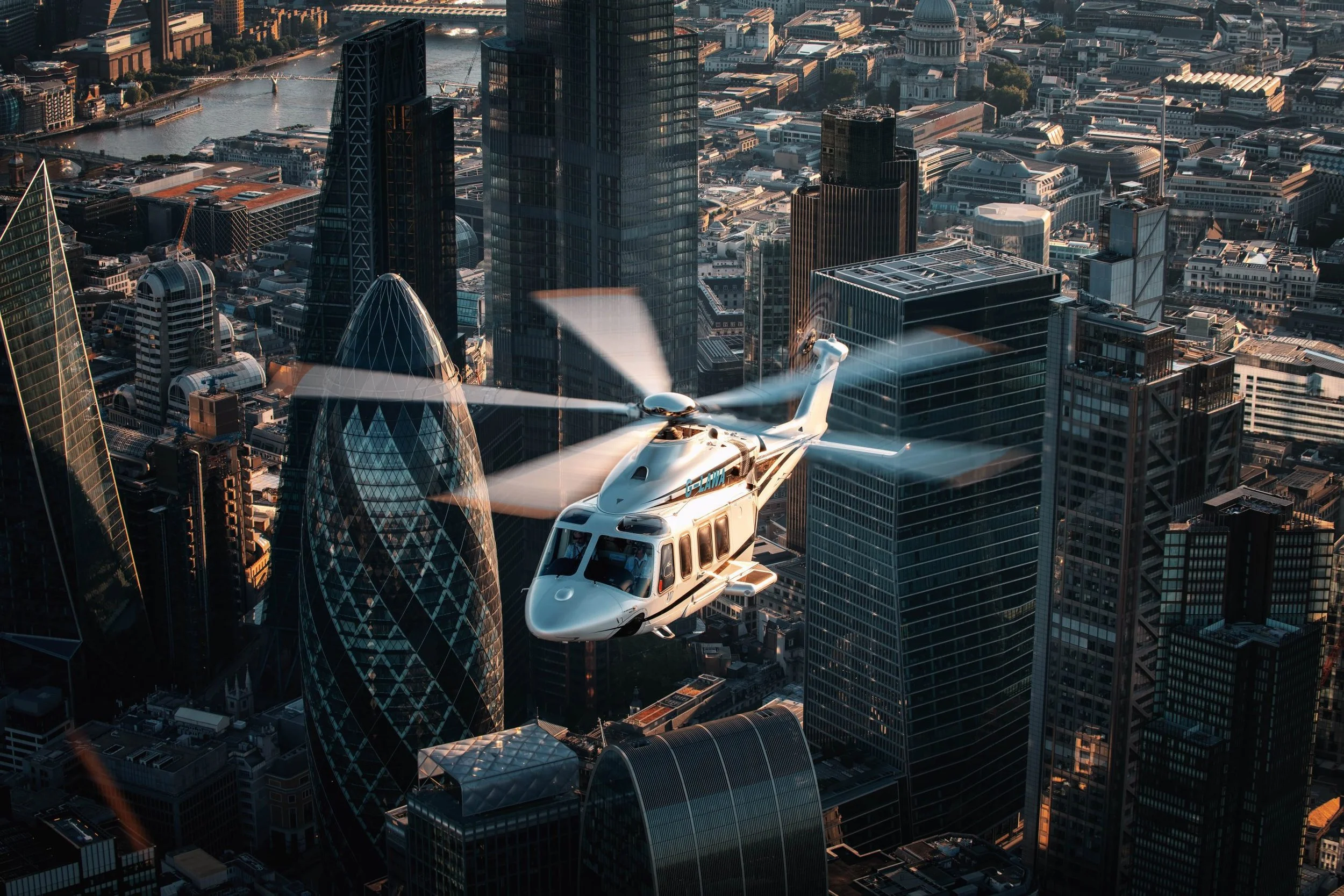 A helicopter flying over a cityscape featuring modern skyscrapers and a distinctive egg-shaped building.