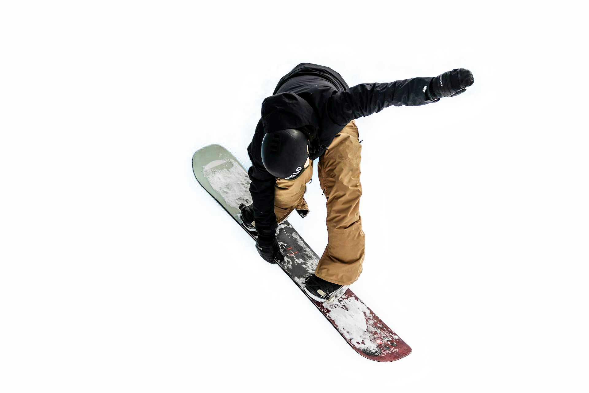 Un skieur en plein saut dans le ciel, portant un casque noir, une veste noire et un pantalon beige, avec des nuages en arrière-plan.