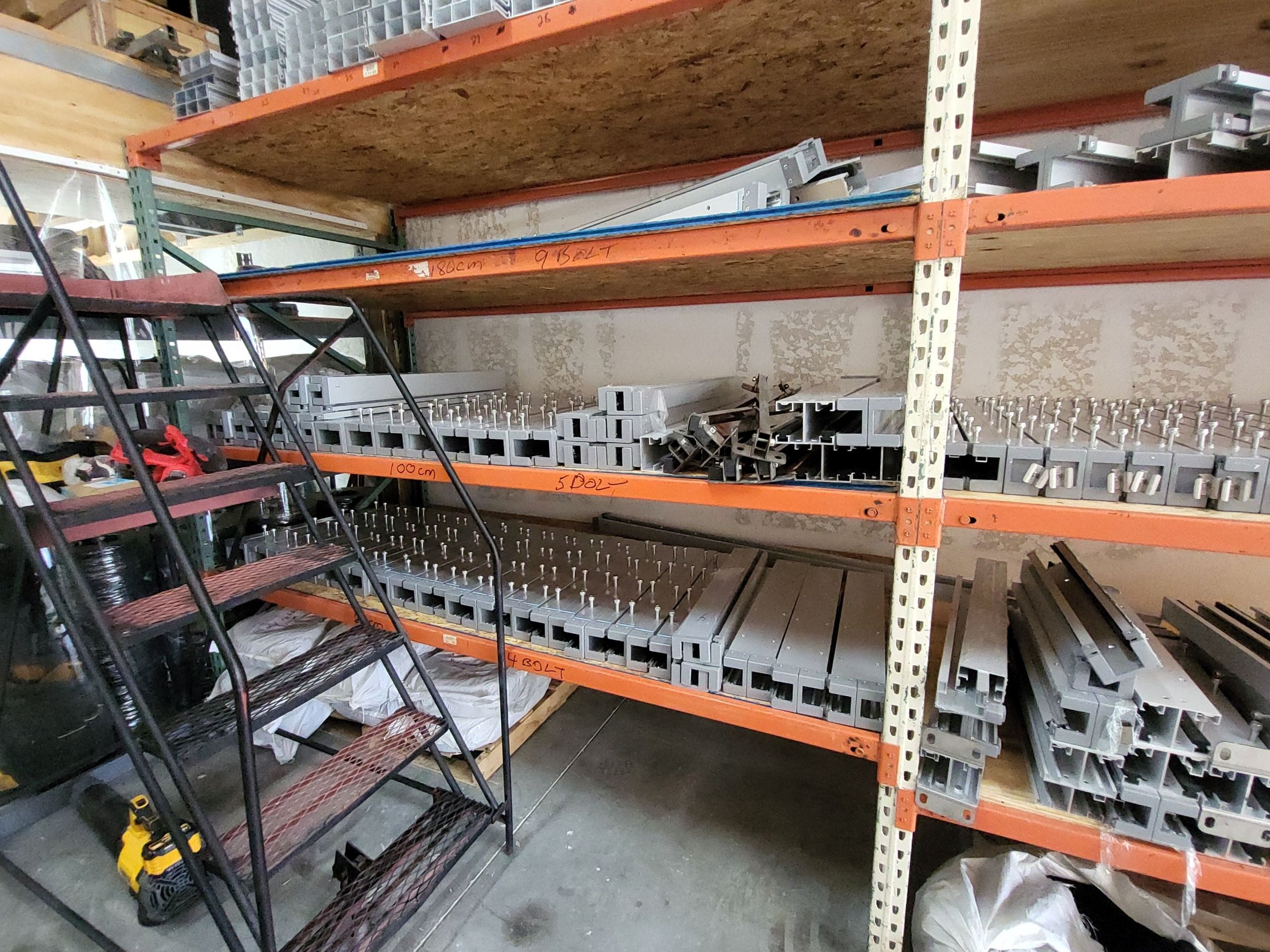 Metal shelves in a hardware store aisle filled with metal parts, brackets, and tools.