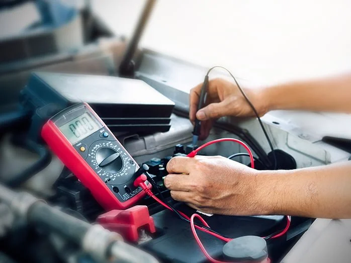 Person using a multimeter to test a car battery