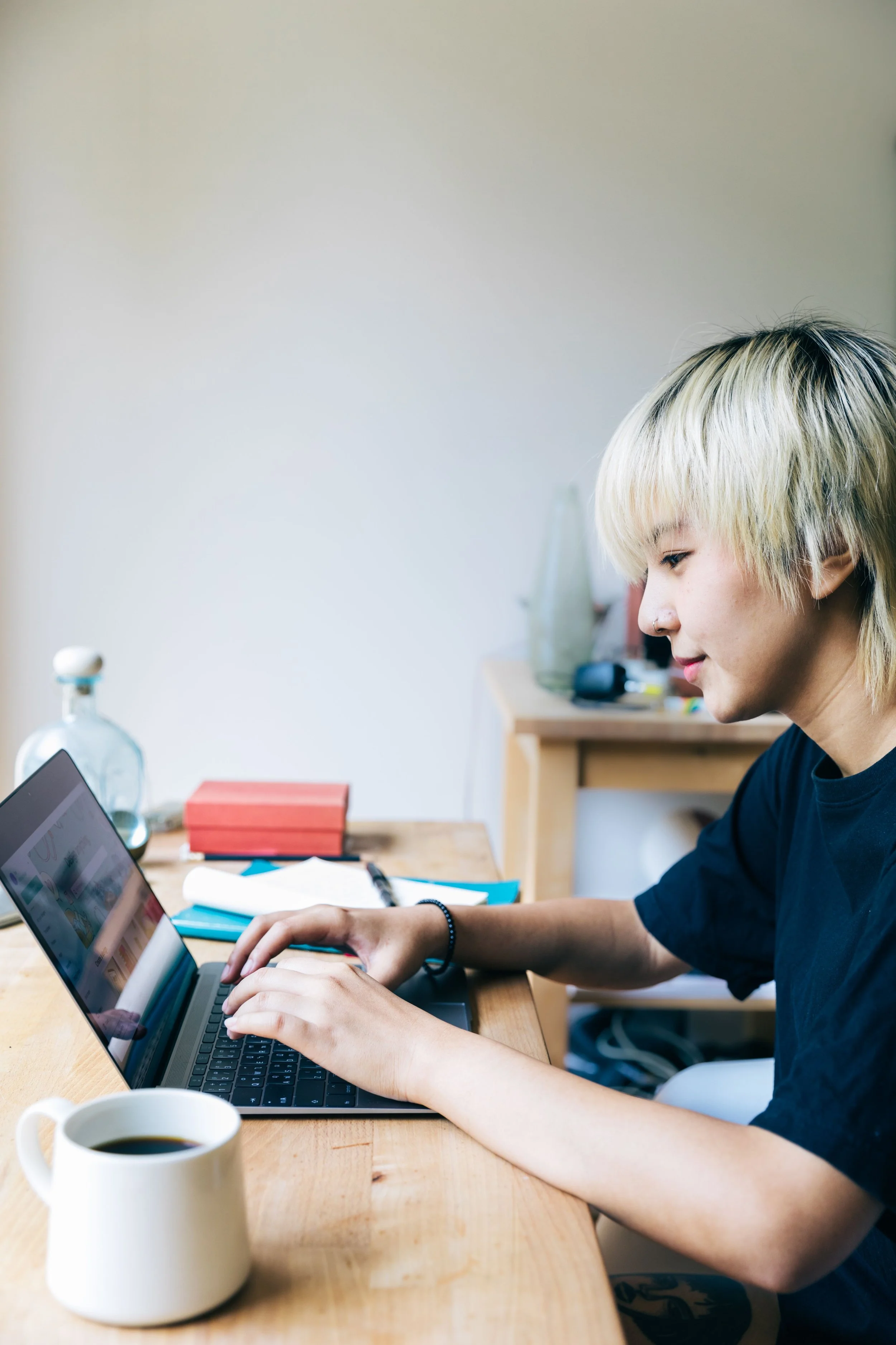 Young man with a smile at a desk using a laptop