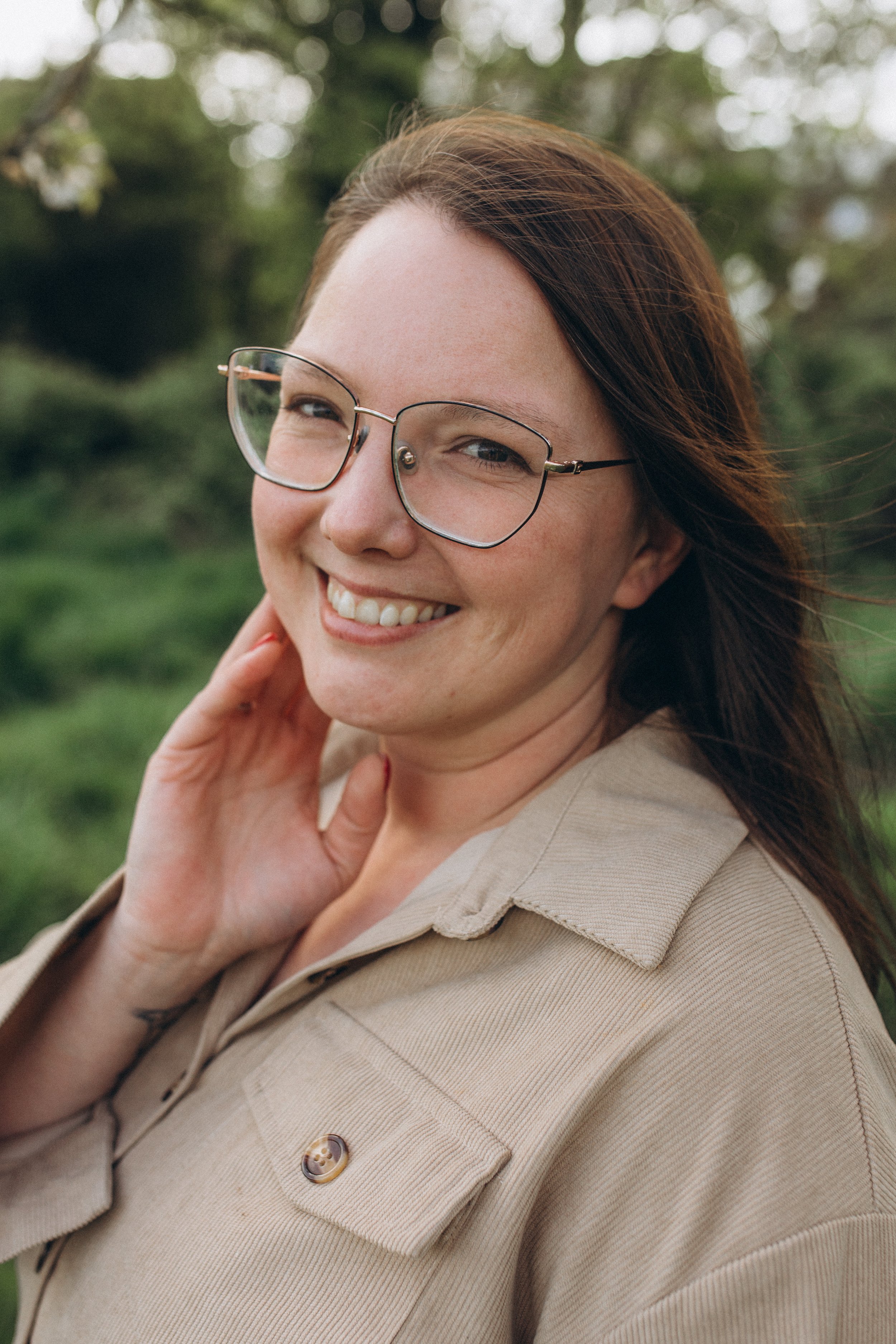 Lächelnde Frau mit Brille im Freien, nah an der Kamera fotografiert.