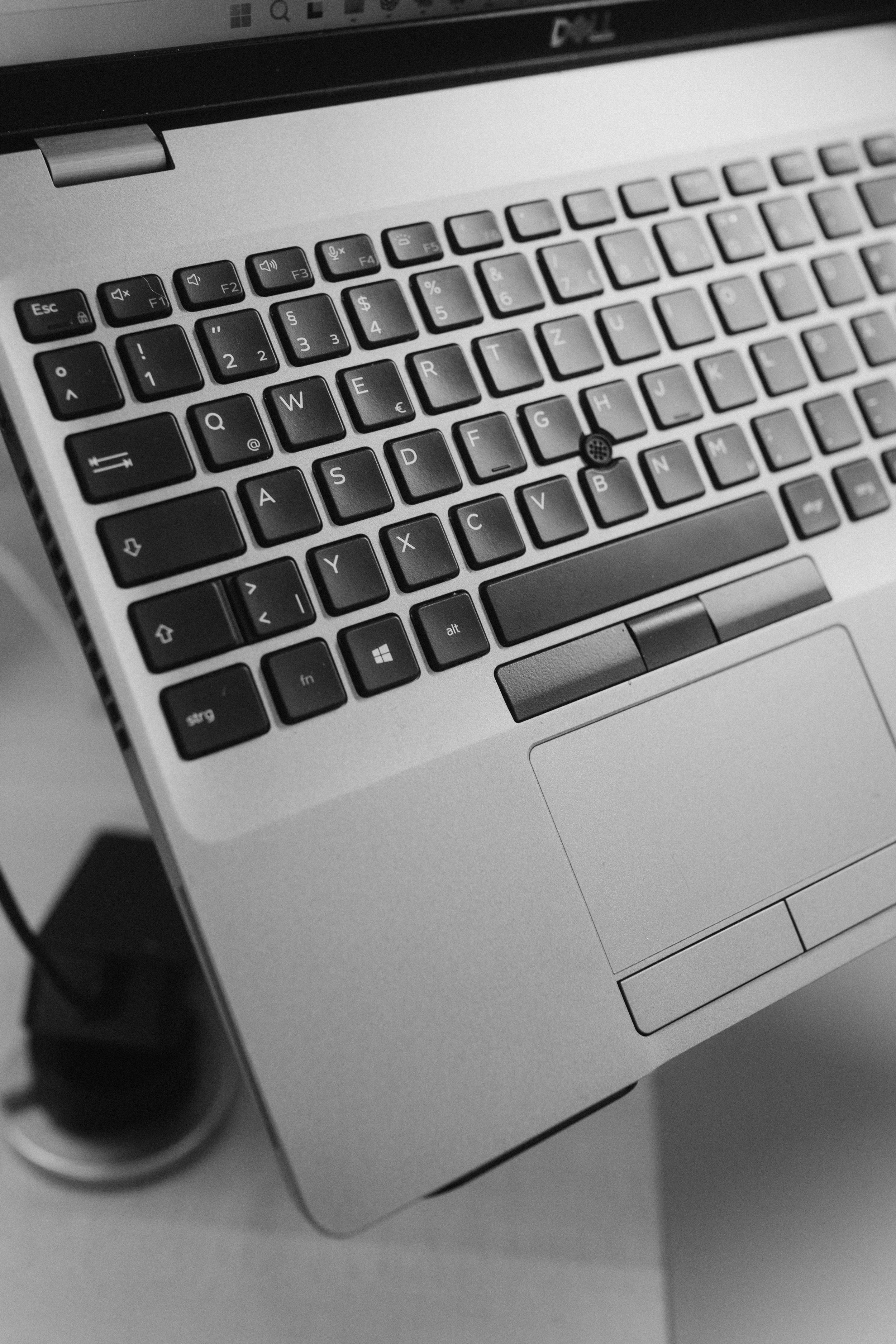 Schwarze Tastatur eines Laptops mit einem Touchpad in einem silbernen Gehäuse, der Bildschirm ist angeschaltet.