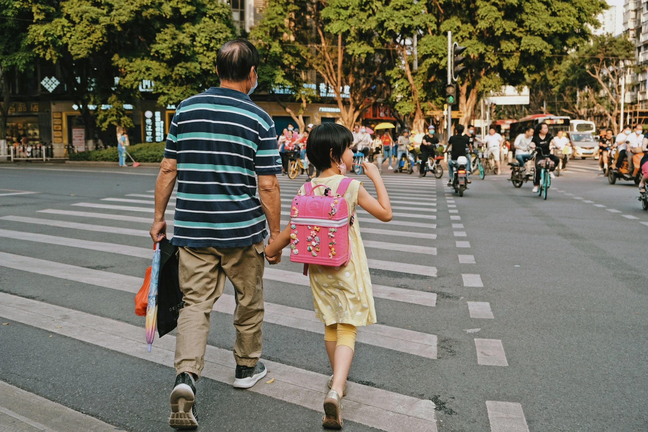 Parent holding a child's hand while crossing the street on Halloween night.