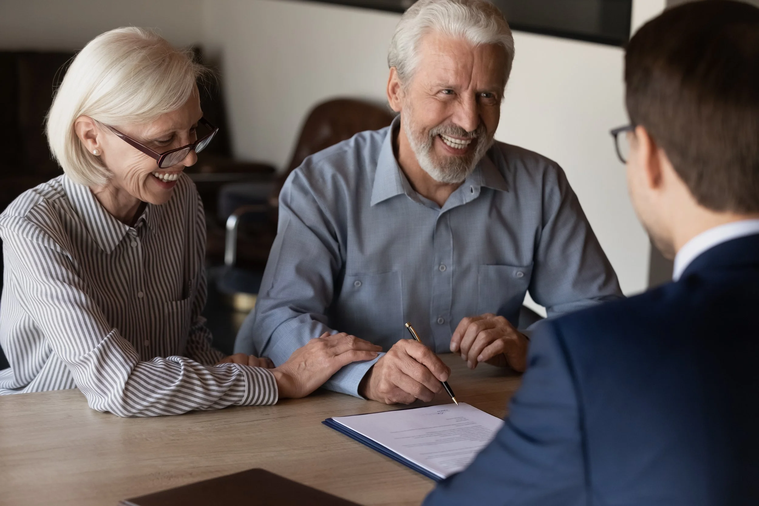 Elderly person signing a living will with an attorney's guidance