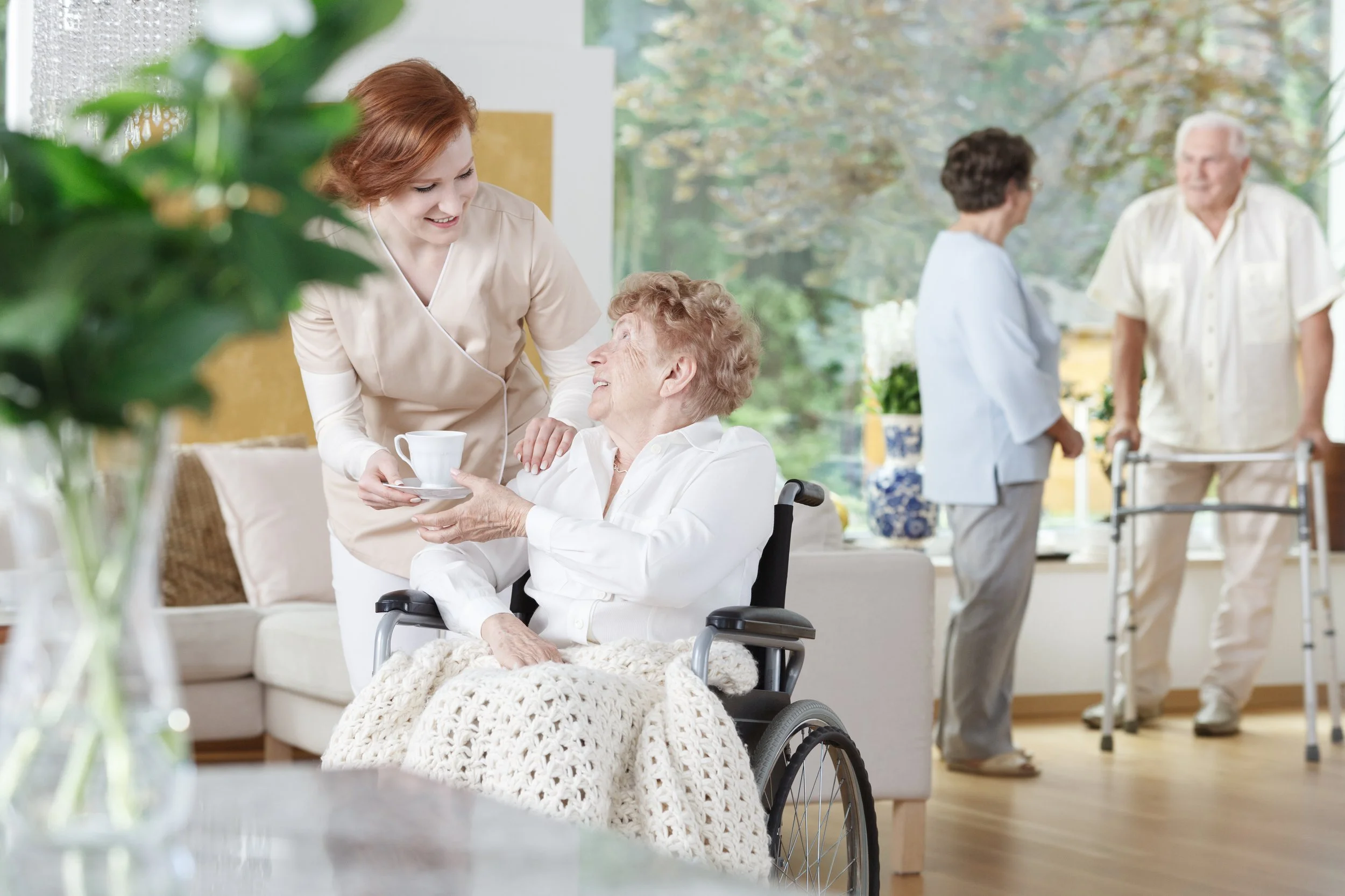 A family member sitting with an older adult during a visit at a long-term care facility.