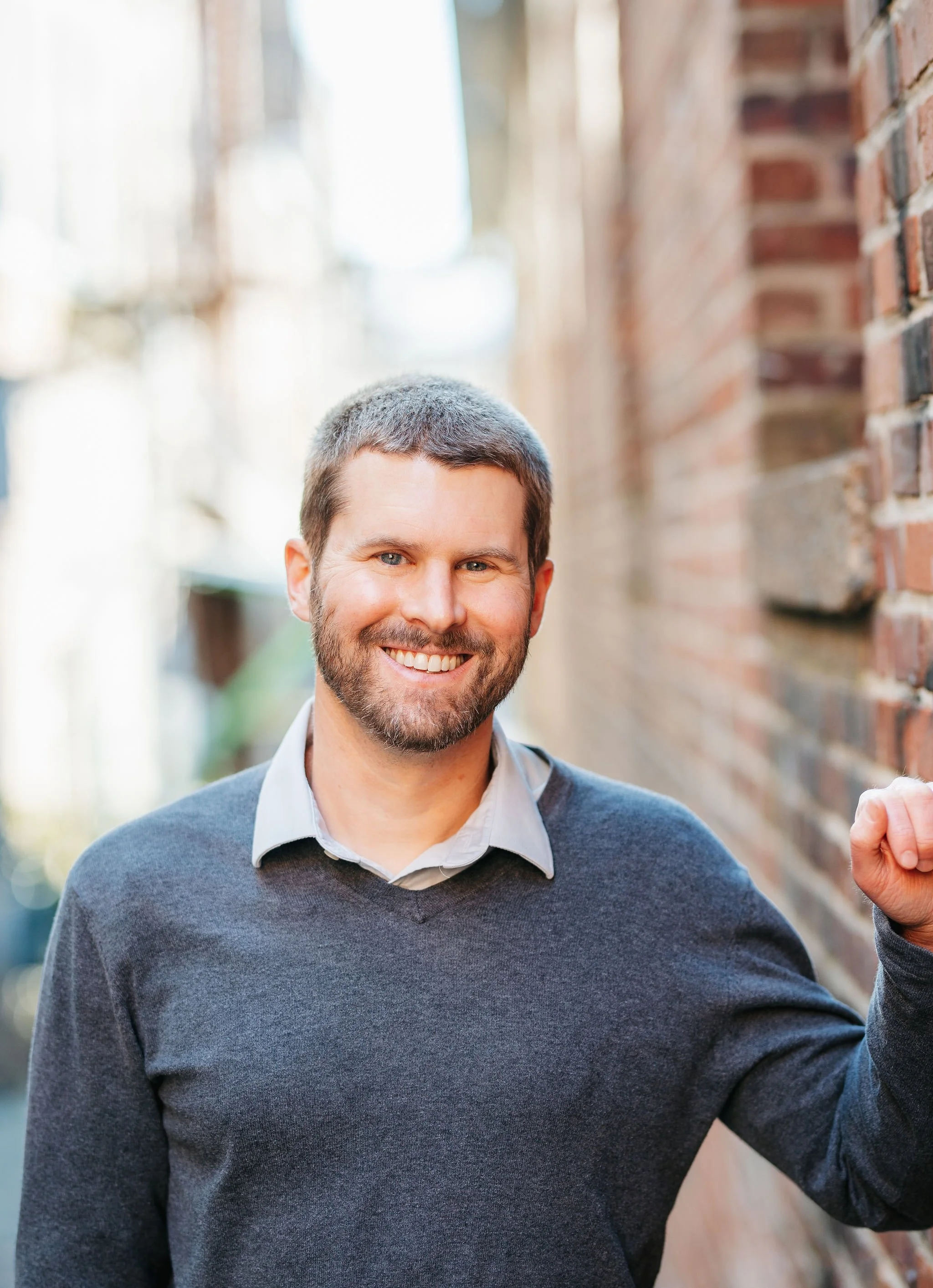 40-year-old white man with sandy blonde hair and short beard, wearing grey sweater.