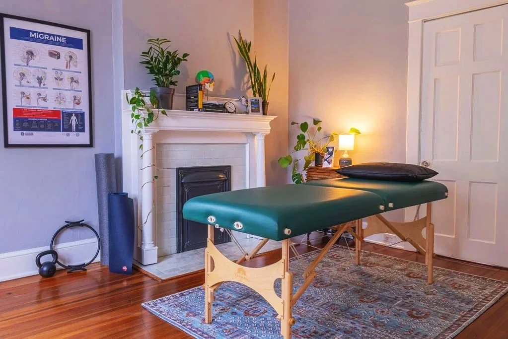Massage treatment table in a gray room with an antique white fireplace mantel