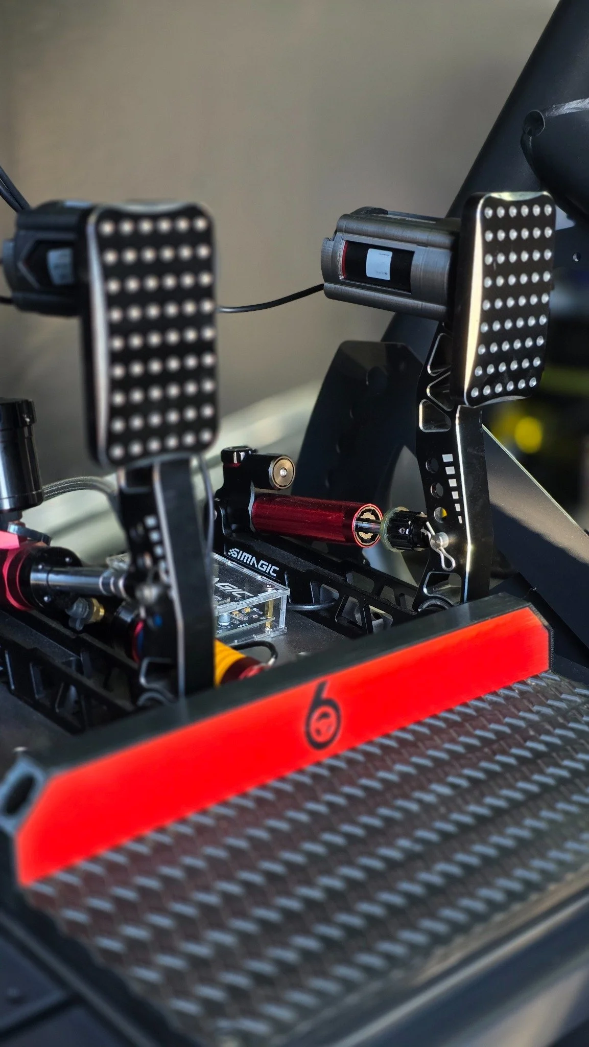 Simagic pedals and Turn 6 branding on a racing simulator pedal deck.