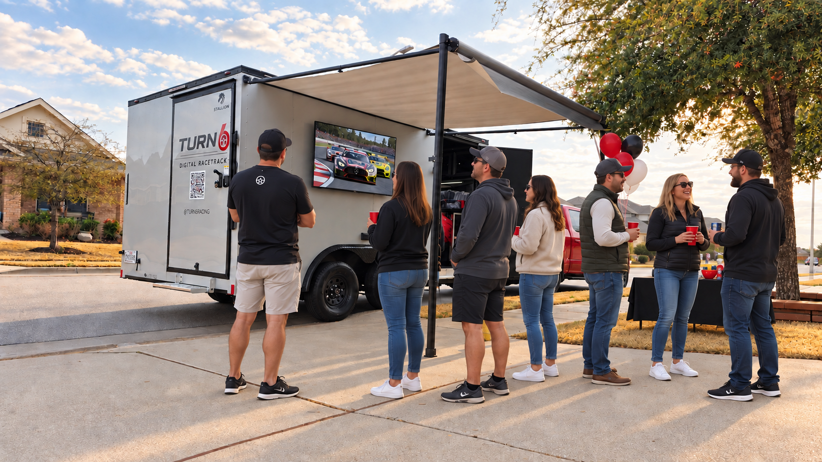 Turn 6 mobile racing party scene with guests beside the trailer and its outdoor race screen.