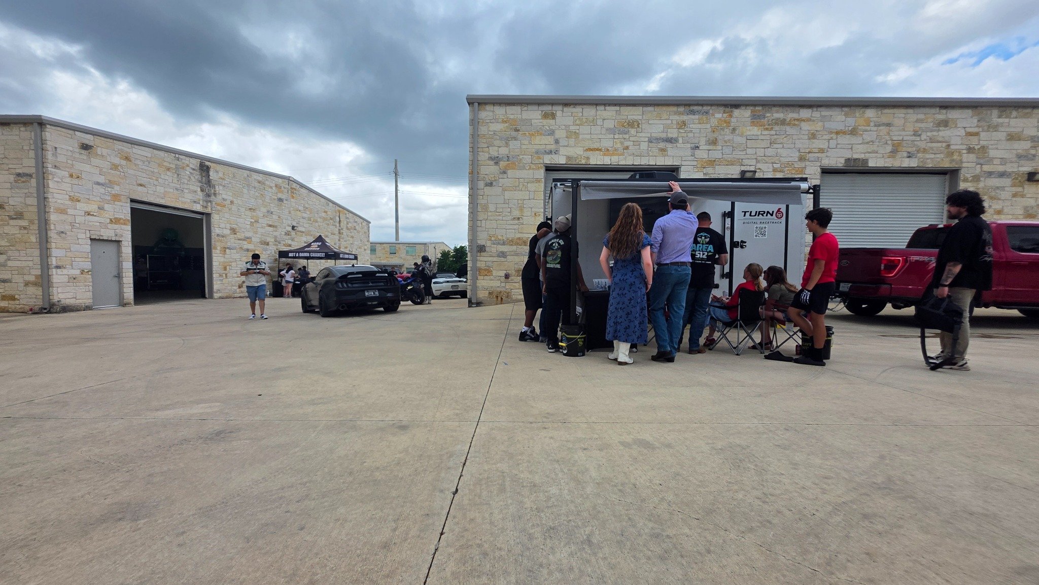 Visitors gathered at the Turn 6 racing trailer during an automotive event.