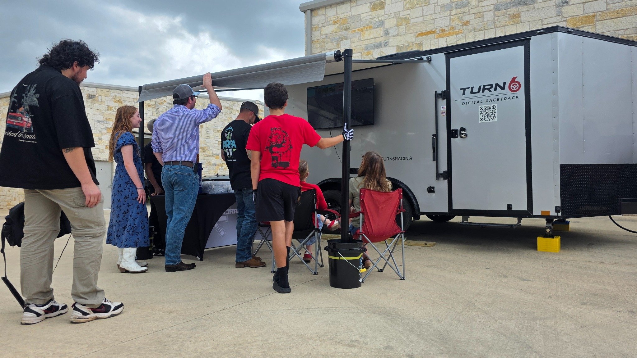 Guests gathered beside the Turn 6 trailer watching the exterior racing screen.