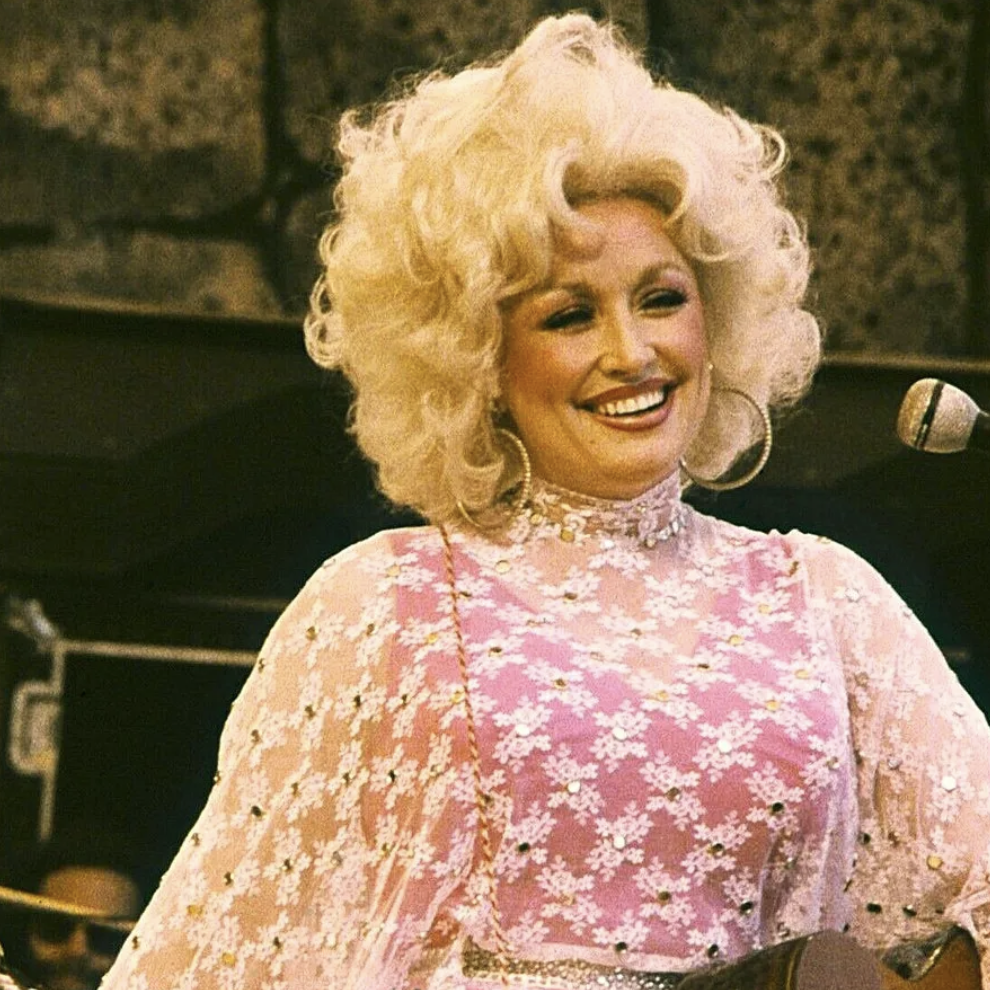 A young Dolly, with big, beautiful, blonde hair, huge hoop earrings, a bedazzled, gauzy fabric, and her signature smile.