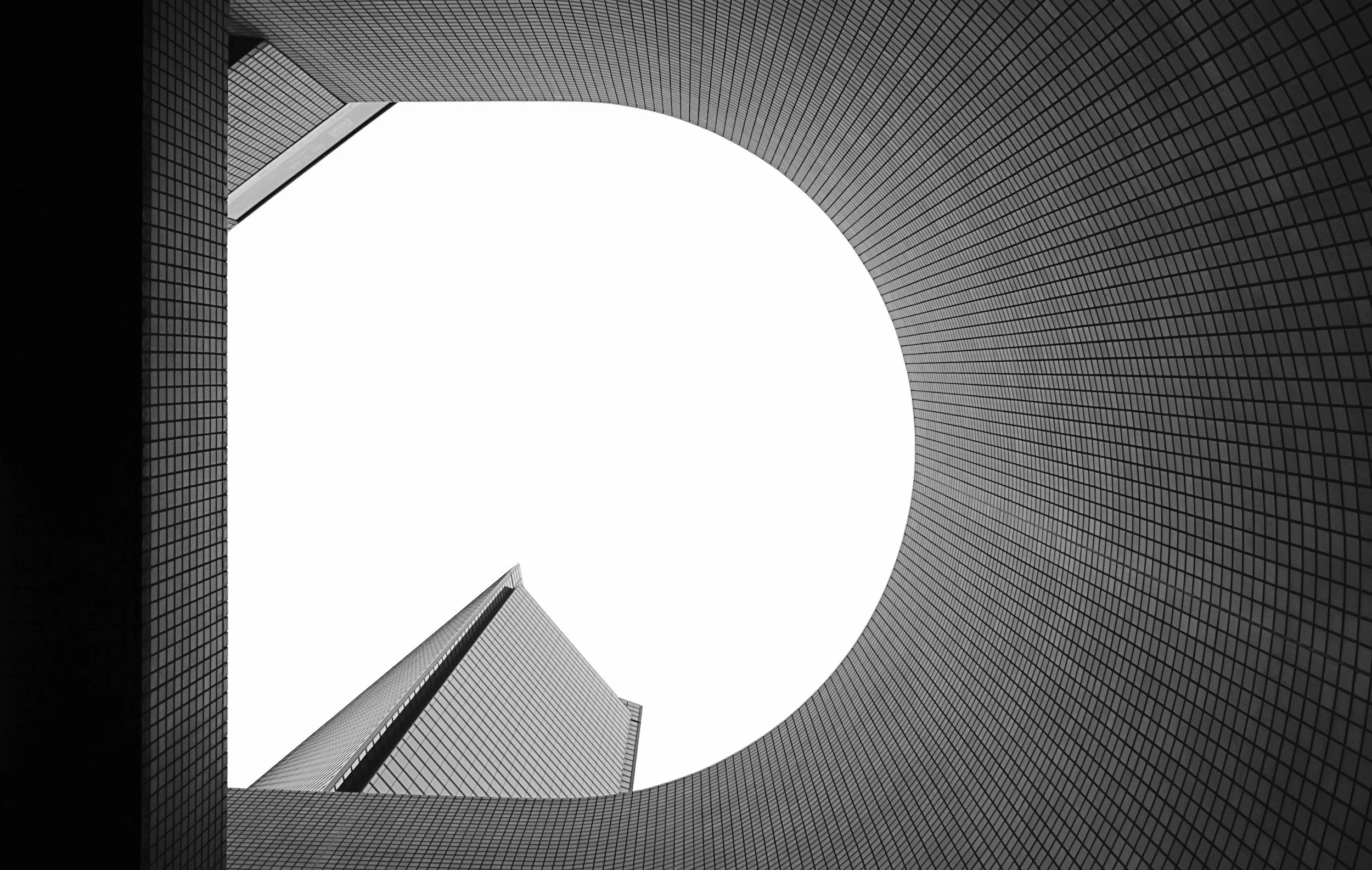 Looking up at modern skyscrapers with geometric designs surrounding a large circular opening in the center.