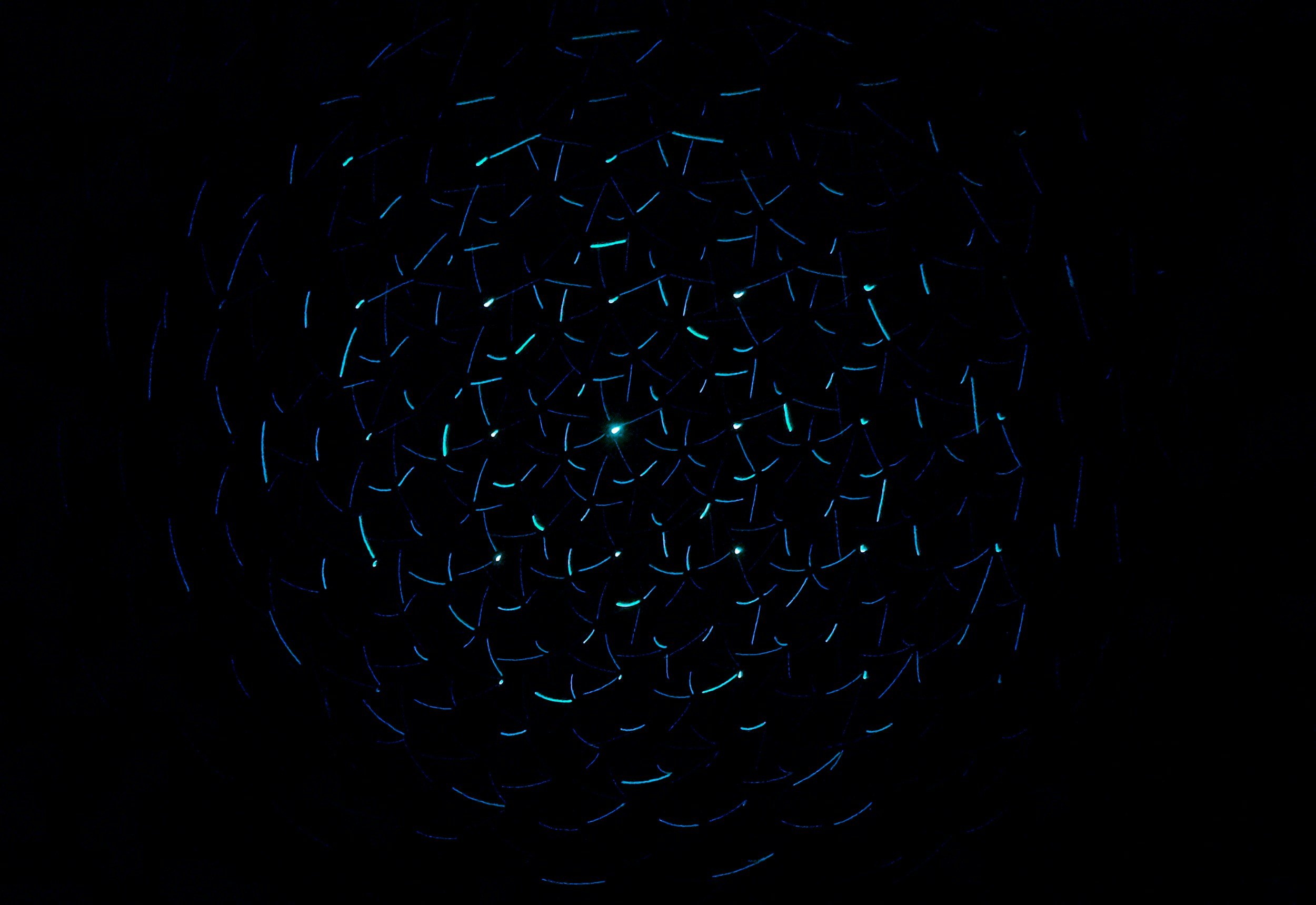 Light trails in the dark forming a circular pattern, with blue and green hues.