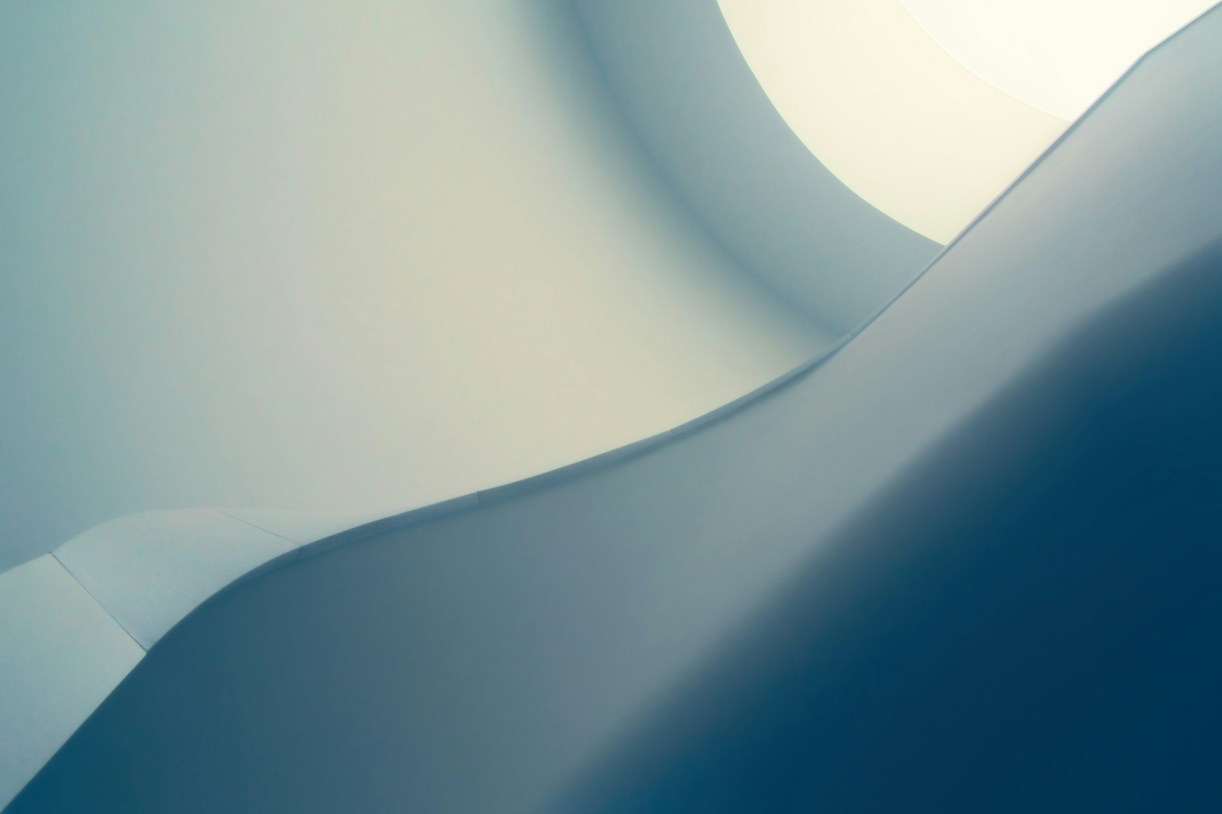 Abstract close-up photograph of smooth, curved architectural surfaces in shades of light blue and white.