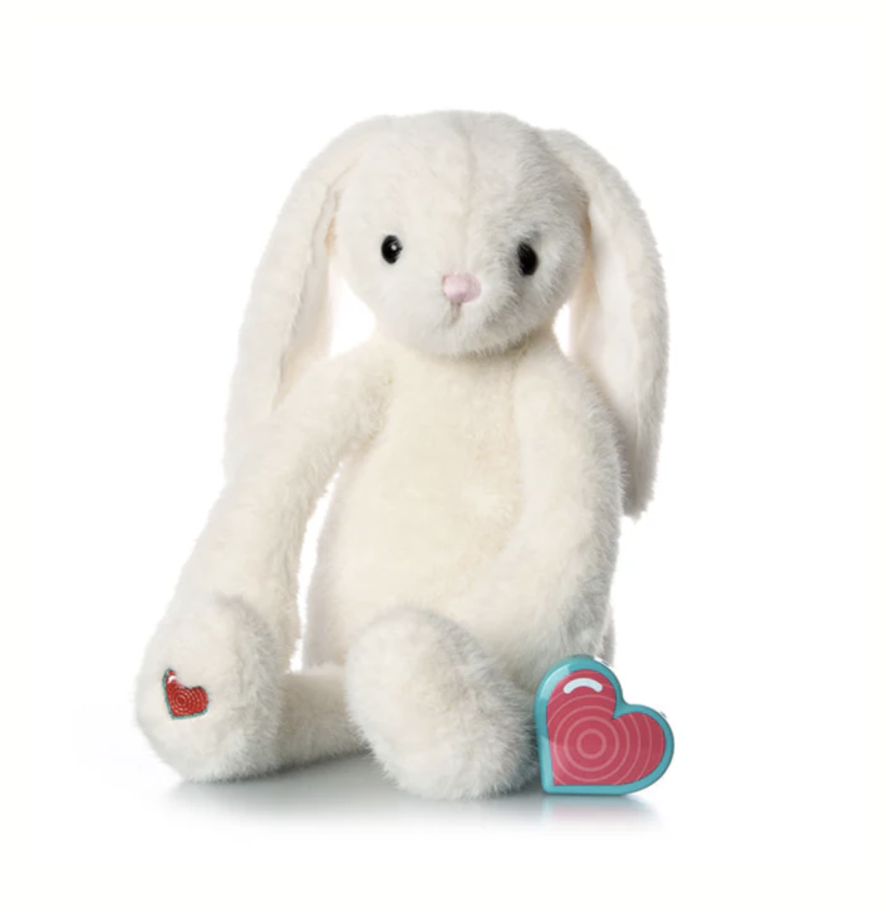 A white plush bunny toy with long ears and black eyes, sitting with a pink heart-shaped box in front of it.